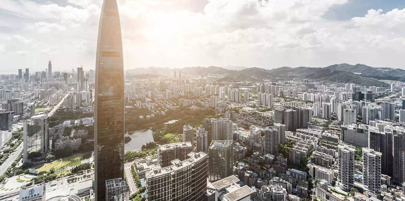 Shenzhen 桌布 壁紙 — 現代城市景觀的鳥瞰圖，以高聳的摩天大樓為主，太陽在其後方閃耀。