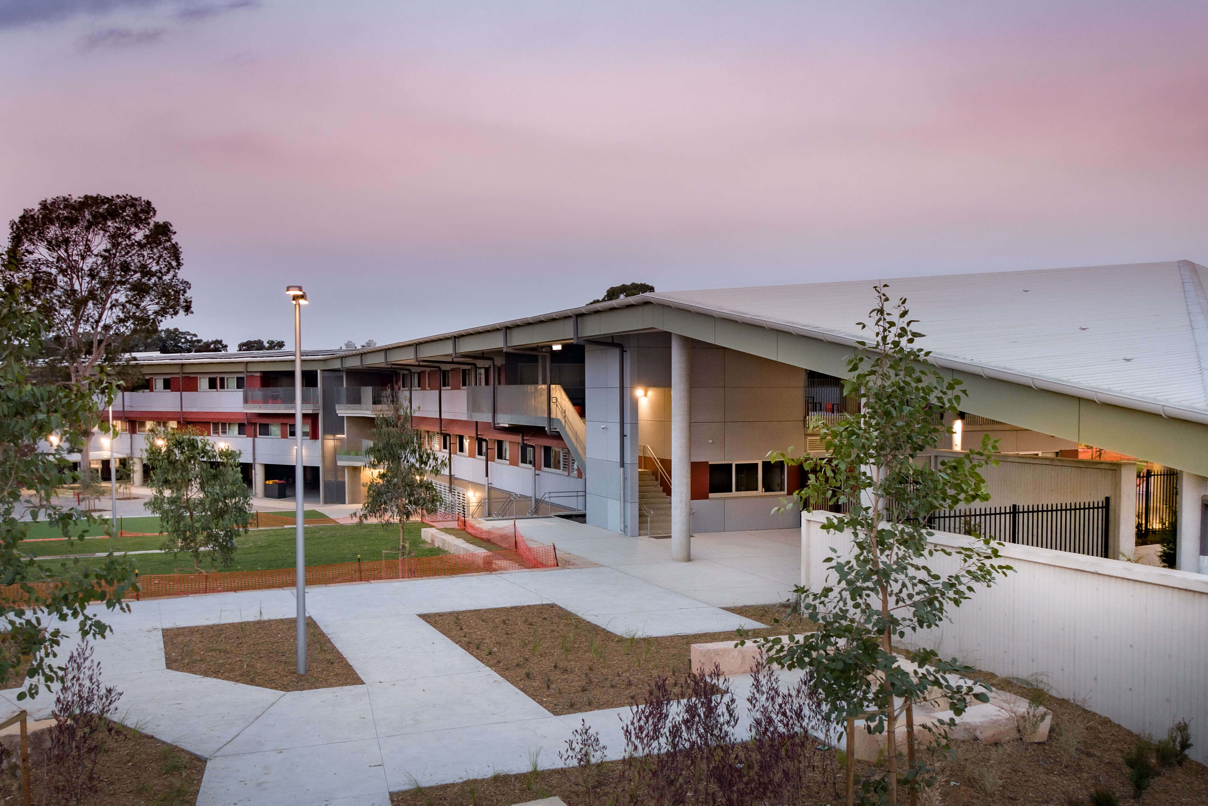 High School 桌布 壁紙 — 現代多層建築，設有陽台和混凝土小徑，在柔和的粉紅色暮色天空下。