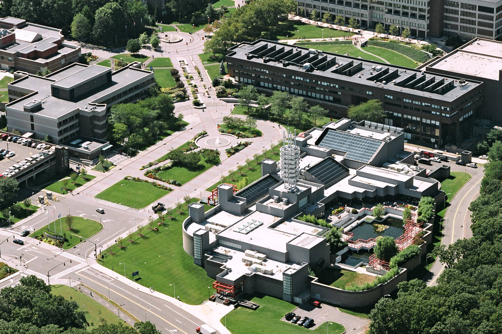 學校 桌布 壁紙 — 現代大學校園的鳥瞰圖，幾何建築、綠色草坪和蜿蜒道路在明亮的日光下。
