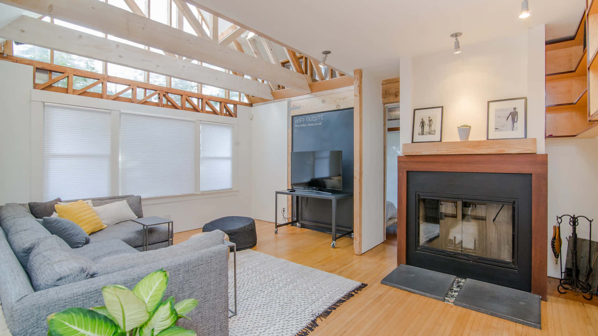 Living Room 桌布 壁紙 — 現代客廳，配有外露木樑、灰色沙發、壁爐和讓自然光線透入的大窗戶。