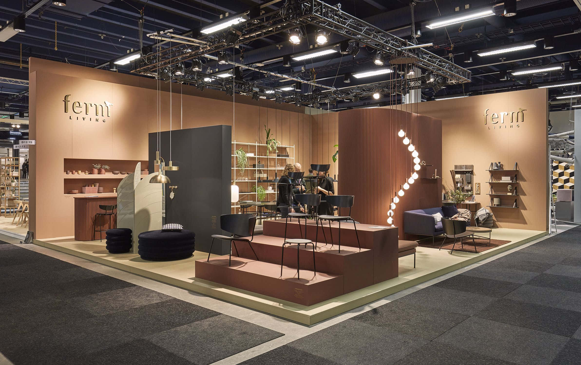 Exhibition 桌布 壁紙 — 現代家具展示廳，設有分層座位、溫暖照明和簡約裝飾，下方為裸露的工業天花板。