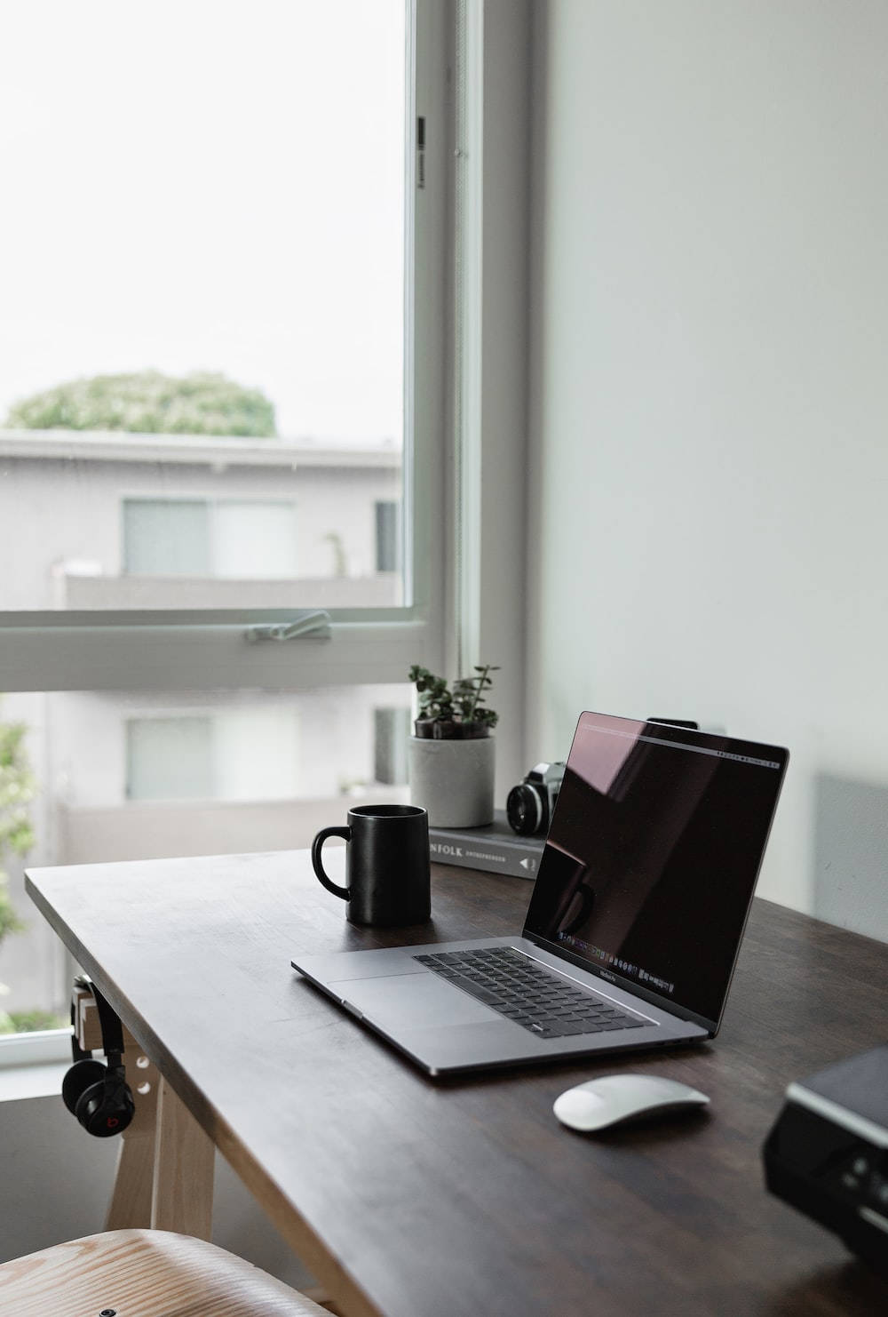 Best Laptop 桌布 壁紙 — 現代居家辦公室的明亮窗邊，一張簡約木桌上放著筆記型電腦、馬克杯、耳機和小盆栽。