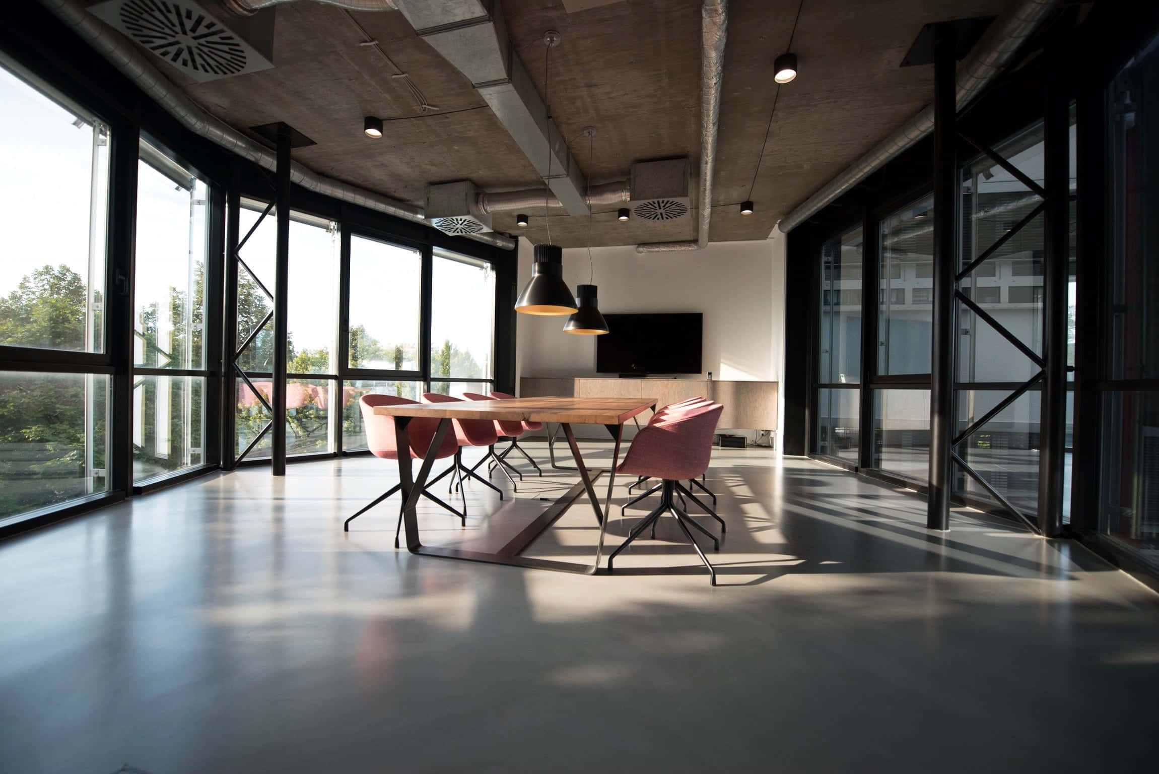 Dining Room 桌布 壁紙 — 現代工業風格辦公室，裸露混凝土天花板，大窗戶將自然光投射在帶有粉紅色椅子的長木桌上。