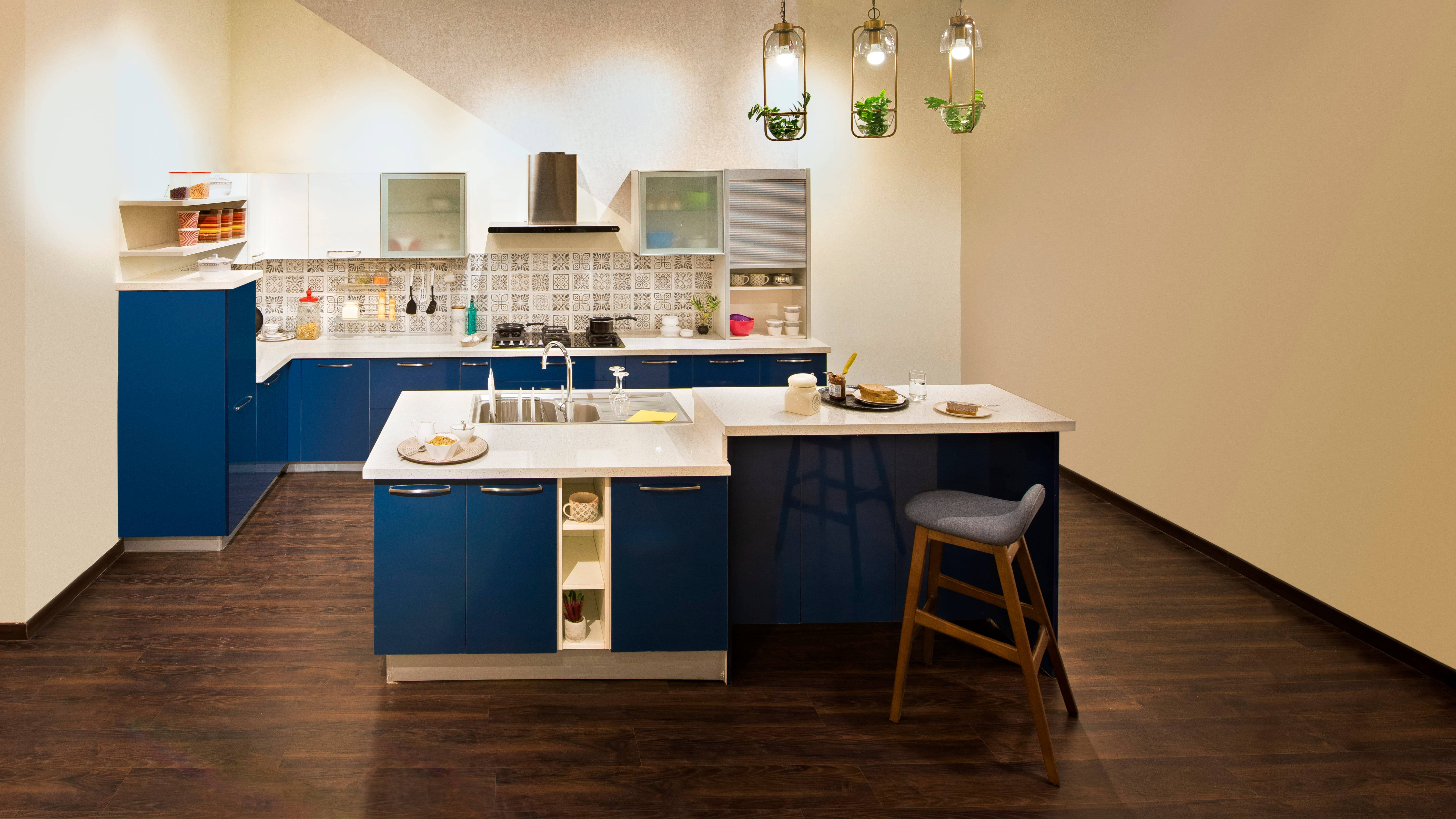 Kitchen Design 桌布 壁紙 — 現代廚房，配有大膽的藍色櫥櫃、白色檯面和溫暖吊燈下的懸掛植物。