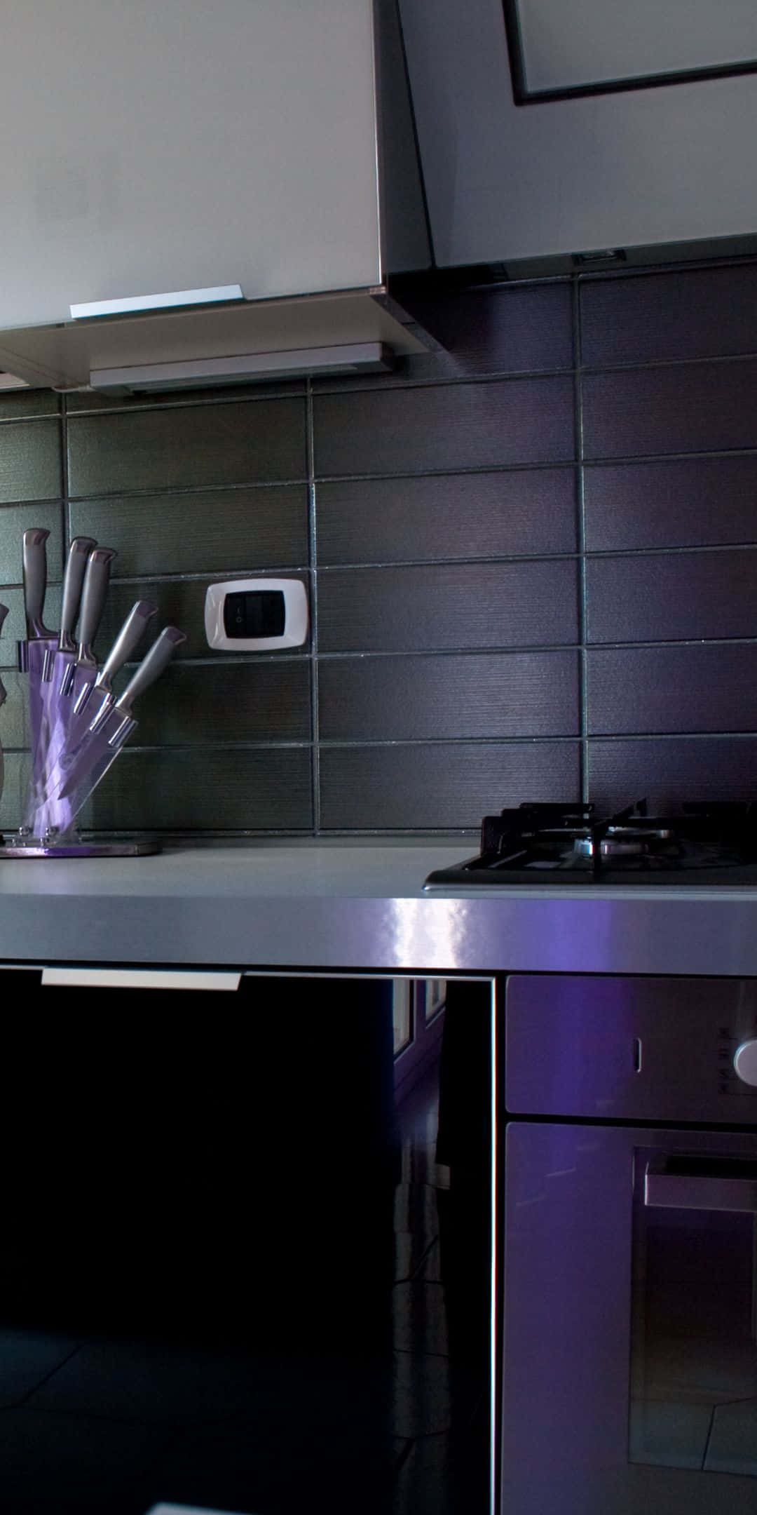 Pixel 3 Kitchen 桌布 壁紙 — 現代廚房，配有時尚不鏽鋼電器和深色瓷磚防濺板，在紫色環境燈光下。