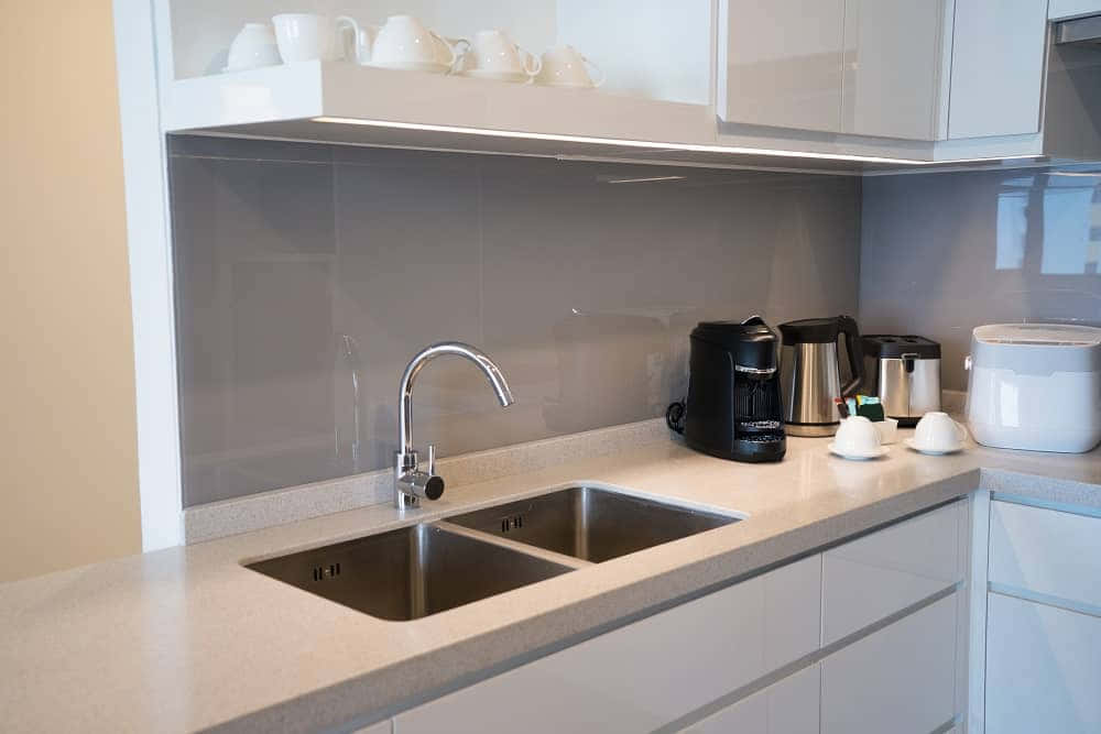 kitchen 桌布 壁紙 — 現代廚房，配有時尚白色櫥櫃、不鏽鋼水槽和玻璃防濺板，在明亮燈光下。