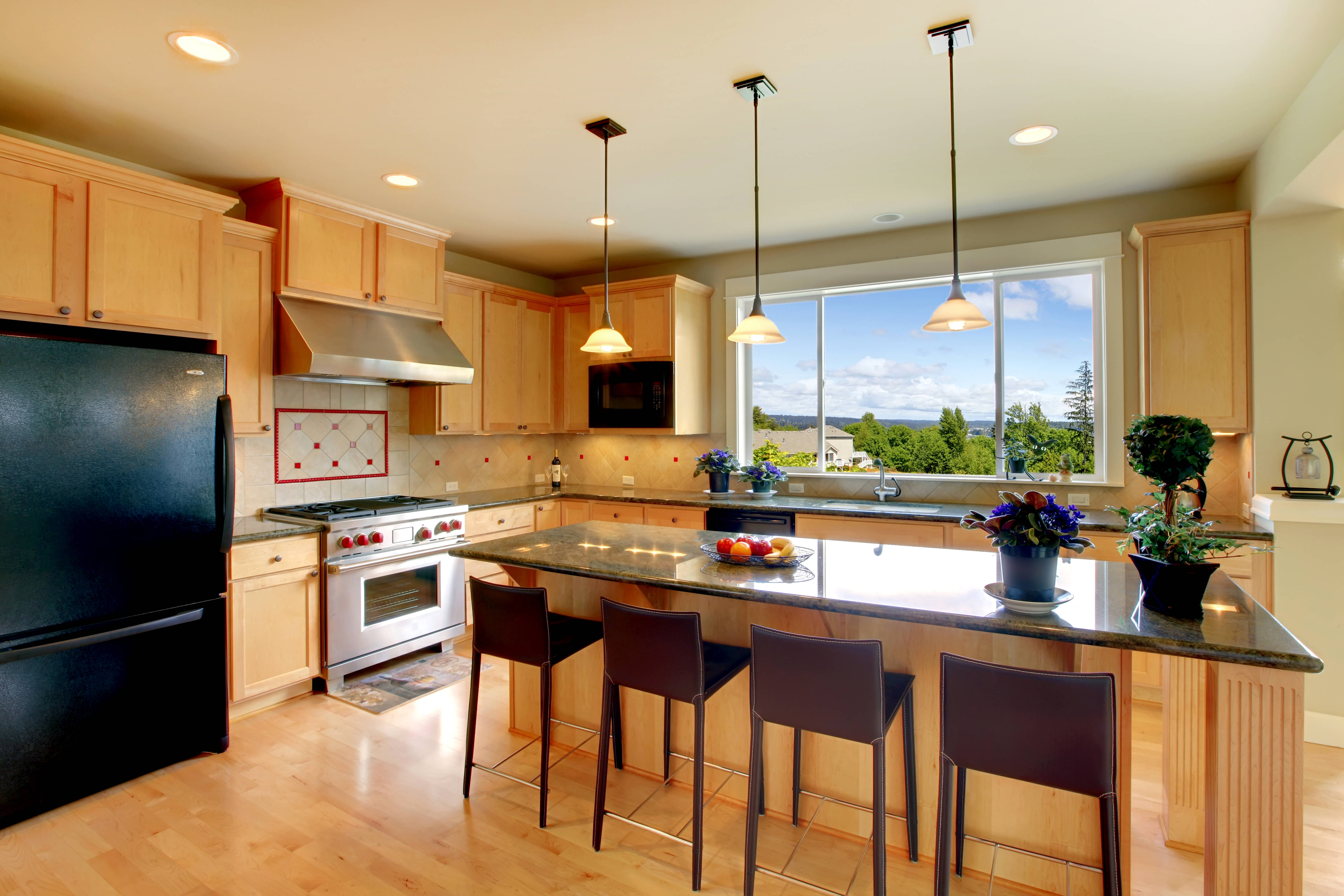 Interior Design 桌布 壁紙 — 現代廚房，配有淺色木櫃、黑色電器和花崗岩中島，透過大窗戶俯瞰綠色山丘。
