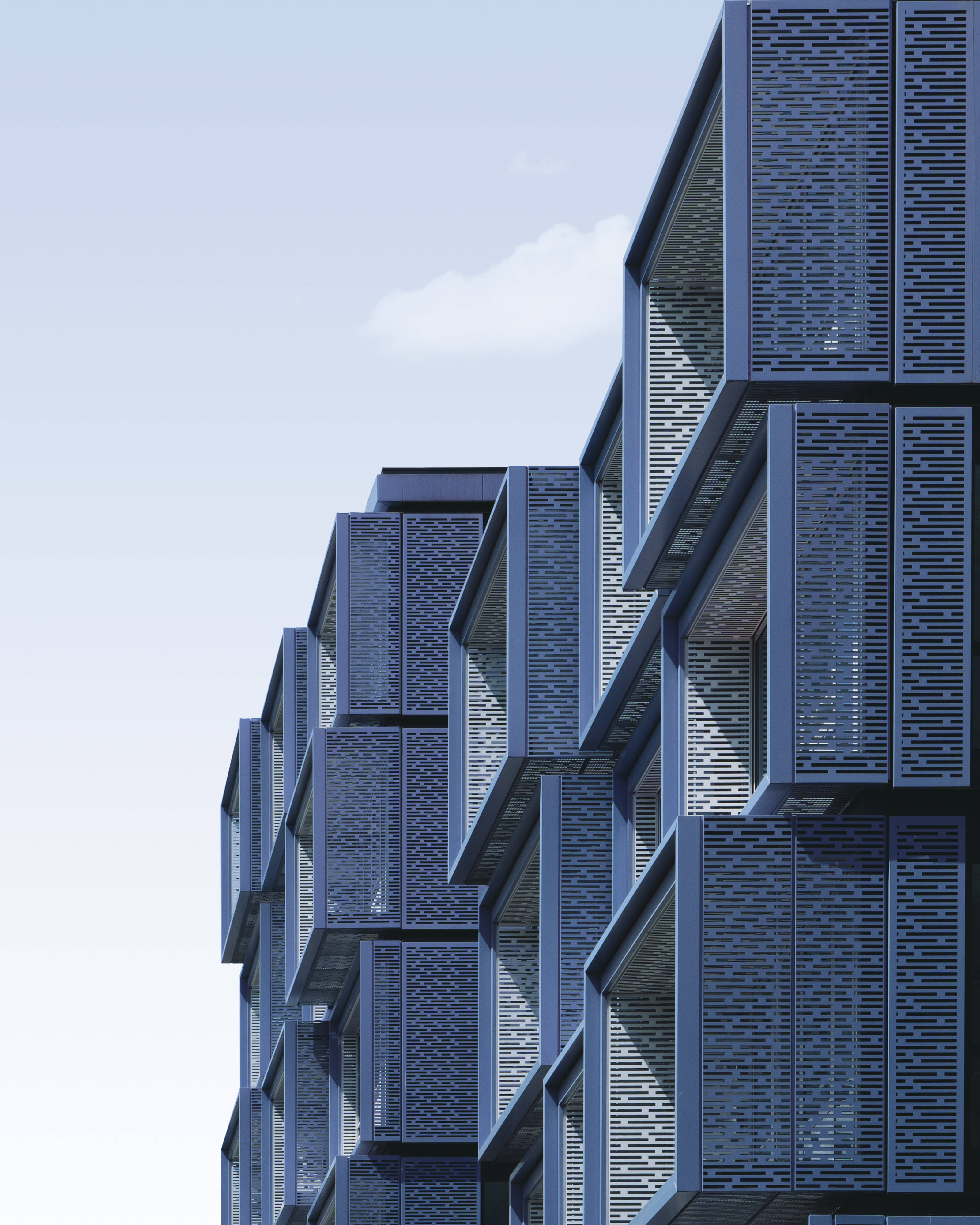 Skyscraper 桌布 壁紙 — 現代建築外牆，帶有幾何形狀的陽台和藍灰色金屬面板，在蒼白的天空下。