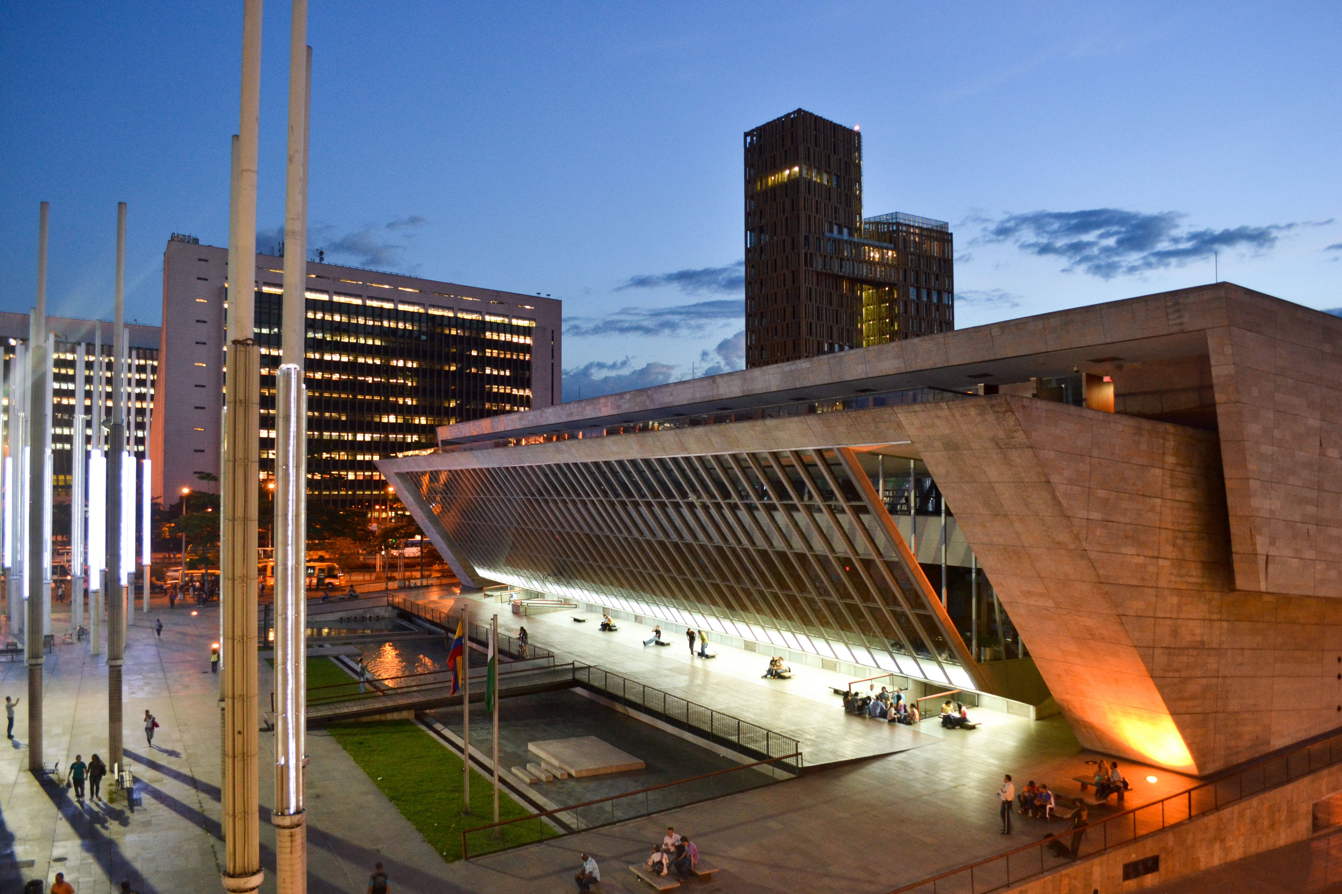 Medellin 桌布 壁紙 — 現代建築奇蹟，在黃昏的城市廣場上，閃爍的玻璃外牆和溫暖的燈光。