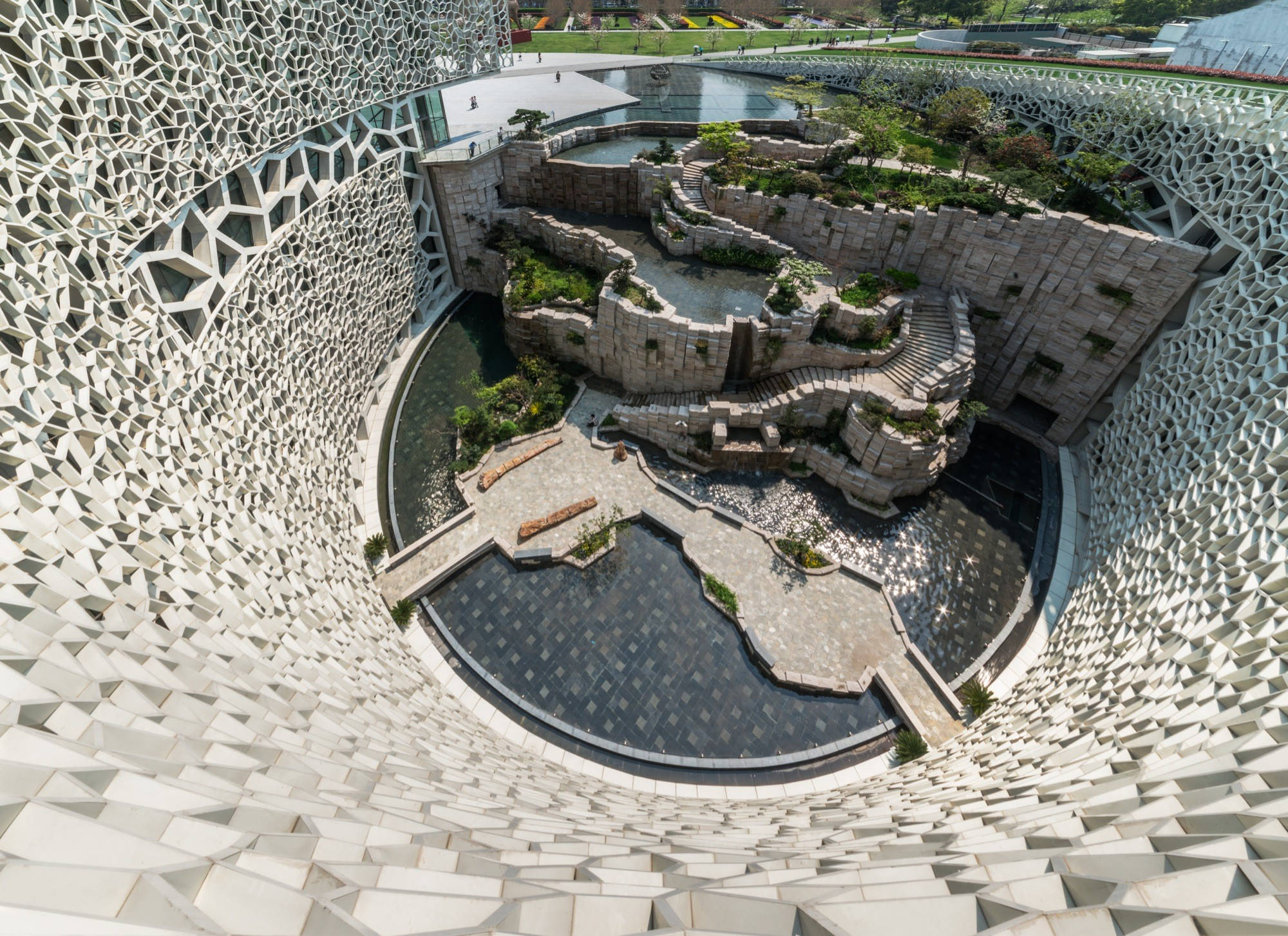 Shanghai 桌布 壁紙 — 現代建築奇蹟的鳥瞰圖，幾何白色格子外殼環繞著一個寧靜的庭院，內有石頭露台、水景和綠植。