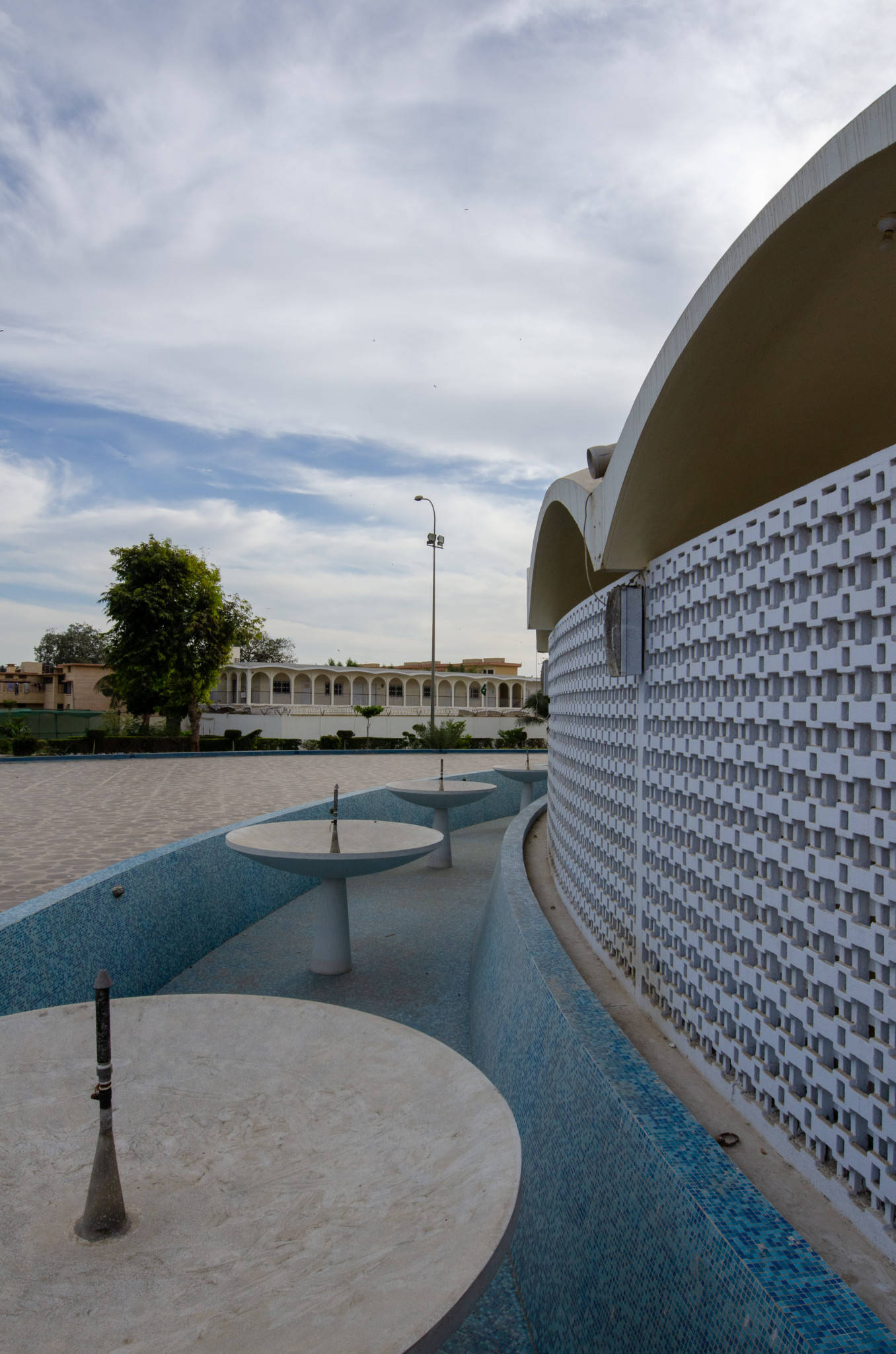 Karachi 桌布 壁紙 — 現代建築庭院，擁有彎曲的白色牆壁和藍色瓷磚水景，天空部分多雲。