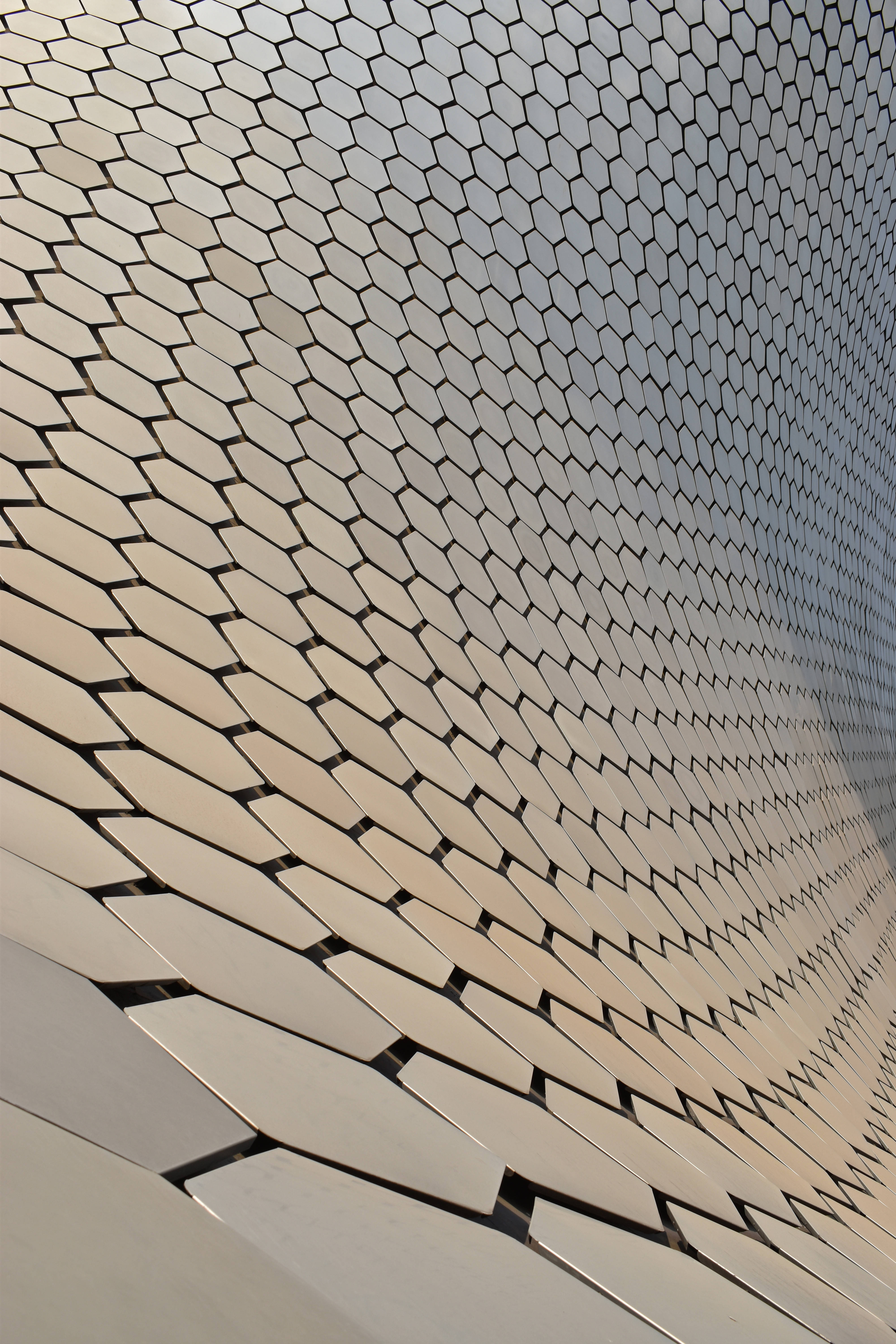 Honeycomb 桌布 壁紙 — 現代建築彎曲金屬六角形面板外牆反射光線的特寫。