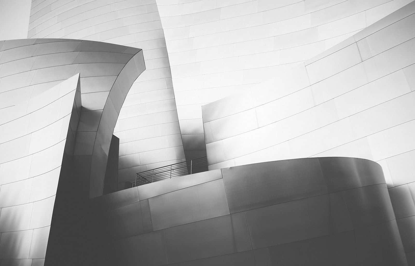 Black And White Architecture 桌布 壁紙 — 現代建築物外牆上流動彎曲金屬表面和銳利幾何陰影的黑白建築照片。