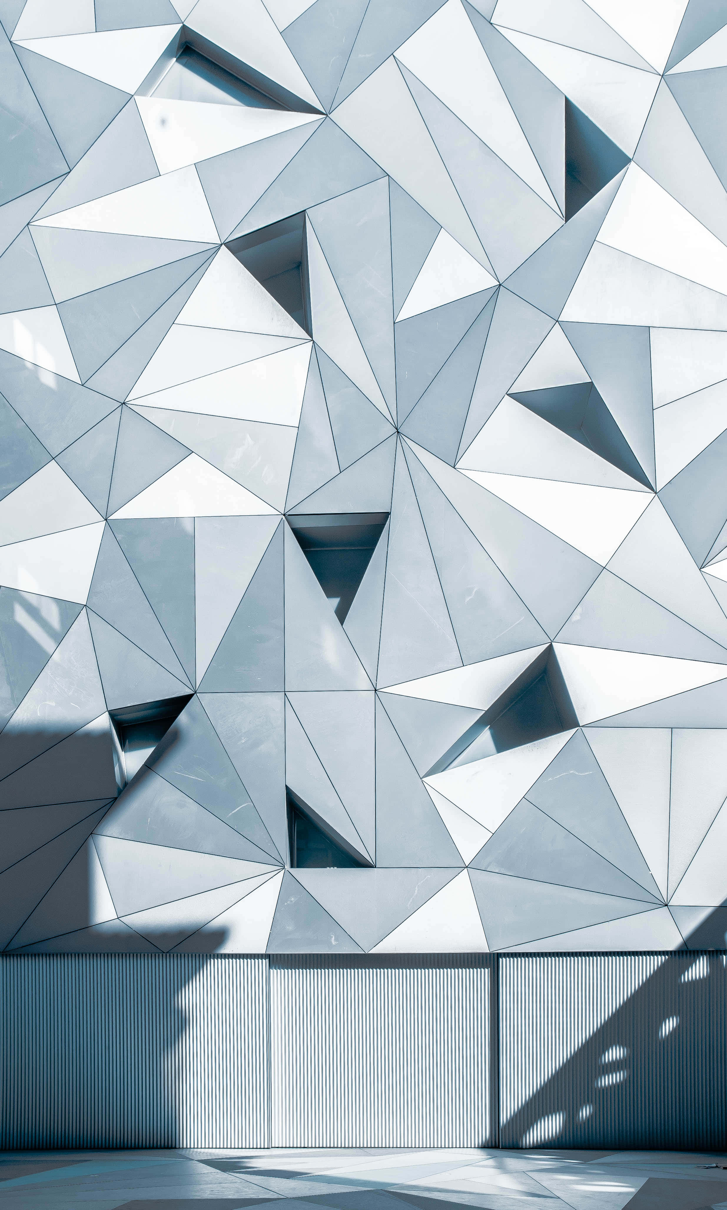 Blue Geometric 桌布 壁紙 — 現代建築物外牆的特寫，具有銳利的幾何三角形面板，採用冷色調的銀色和灰色。