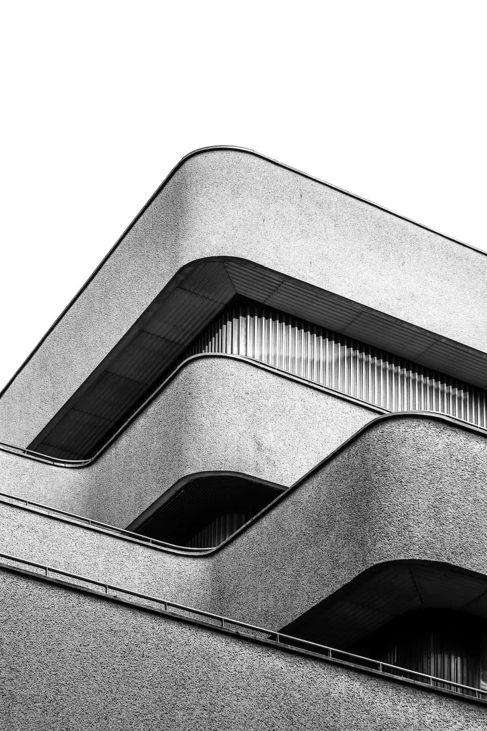 Modernism 桌布 壁紙 — 現代建築物的黑白特寫，展現紋理混凝土外牆，配以大膽幾何曲線和嵌入式窗戶。