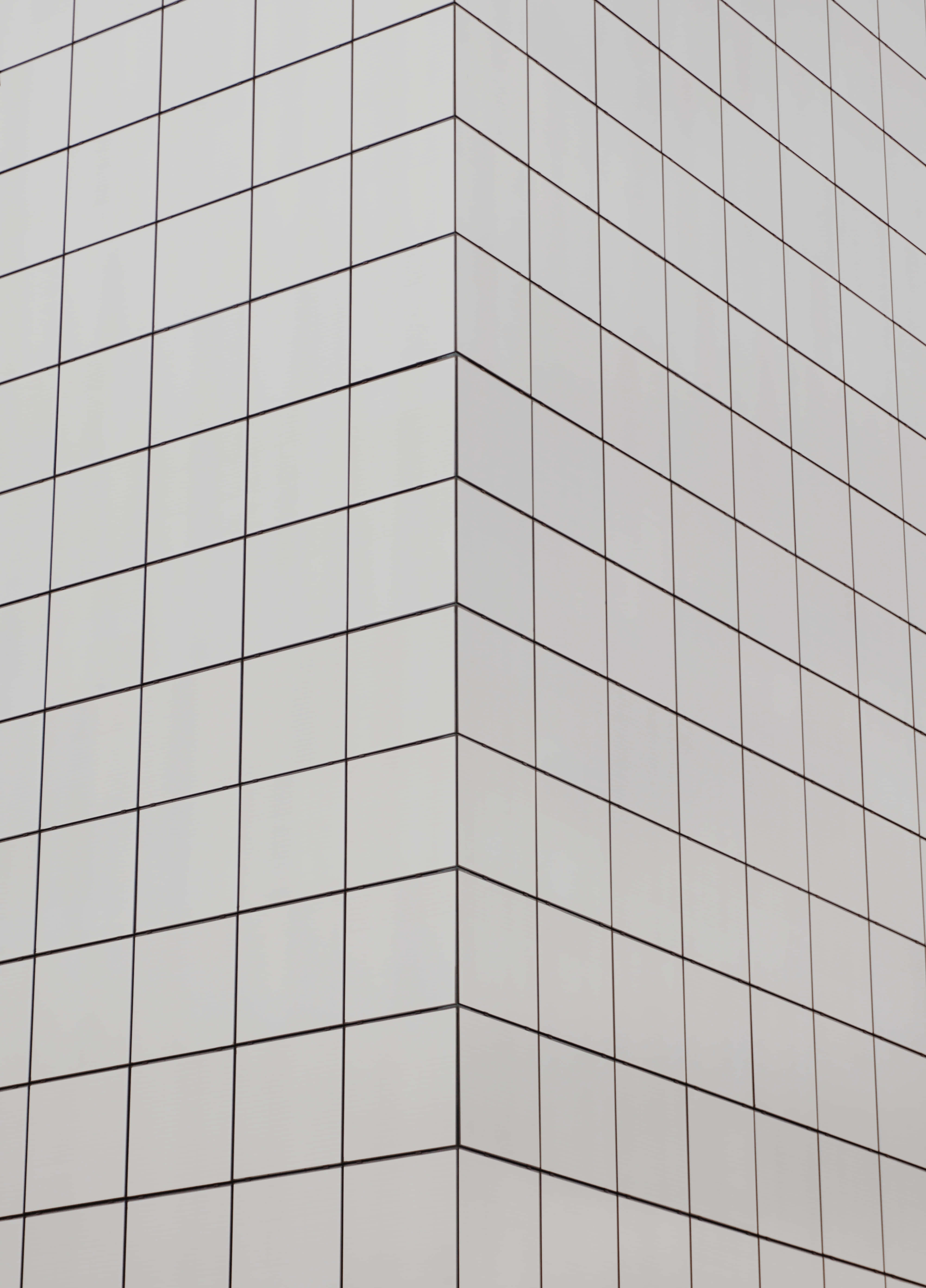 White Square 桌布 壁紙 — 現代建築角落的特寫，淺灰色瓷磚面板和深色網格線形成幾何圖案。