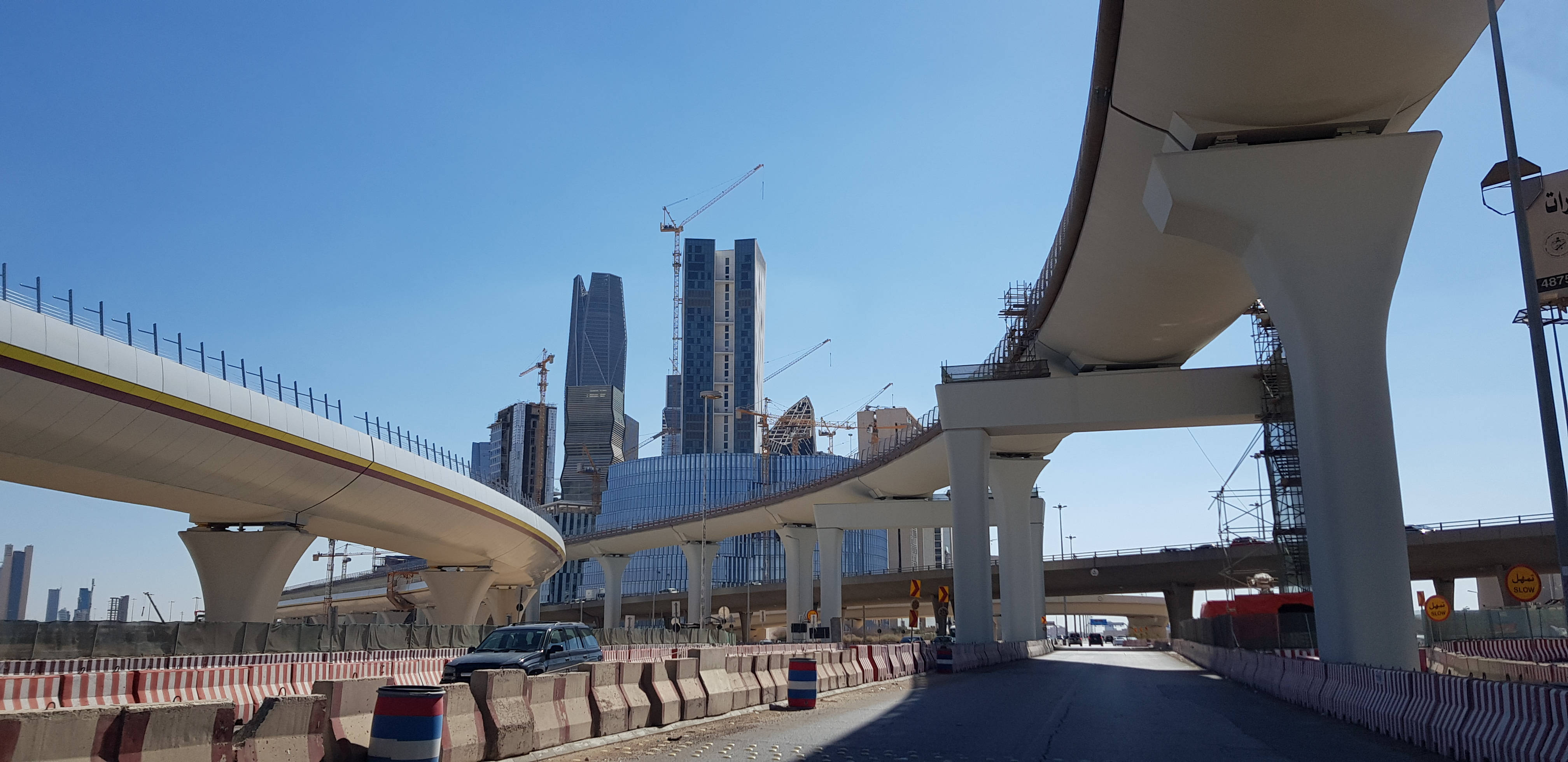 Riyadh 桌布 壁紙 — 現代彎曲的高架高速公路和正在建設中的高聳摩天大樓在晴朗的藍天下延伸。