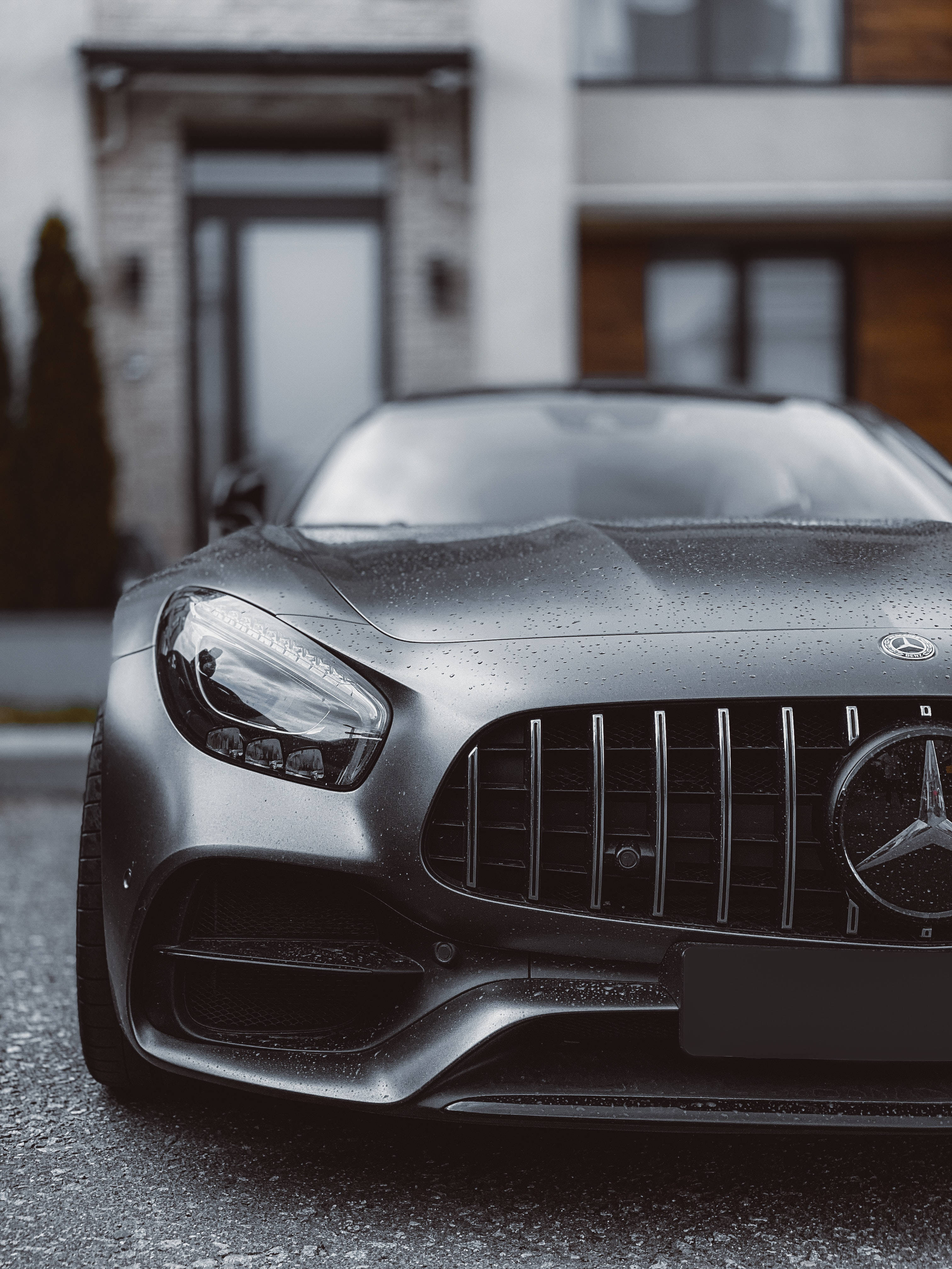 4K iPhone 6 plus 桌布 壁紙 — 現代房屋前停泊的消光黑色 Mercedes-AMG 跑車特寫，引擎蓋上閃爍著雨滴。
