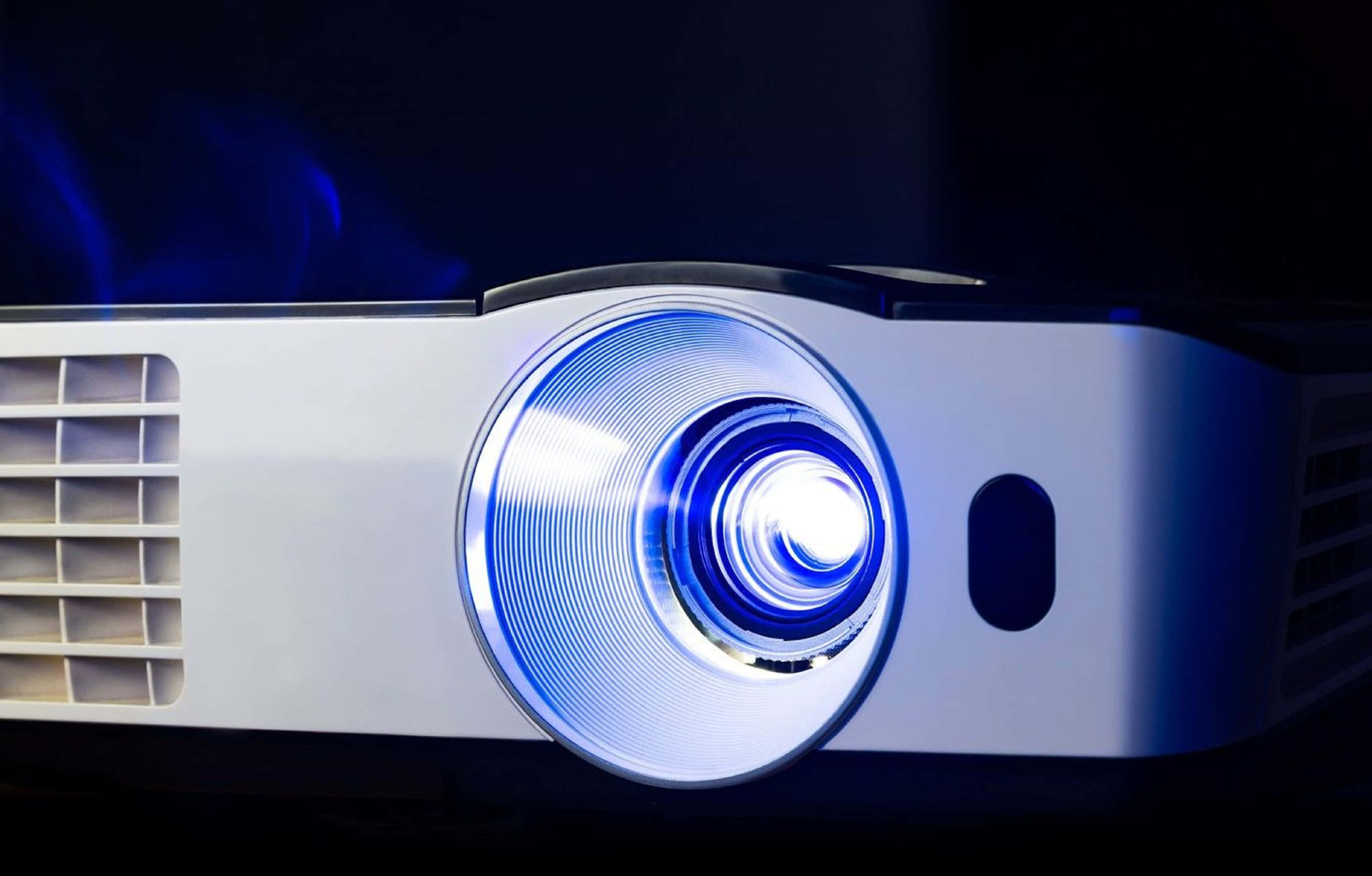 4K Projector 桌布 壁紙 — 現代投影機的特寫，在黑暗背景下發出明亮的藍光。