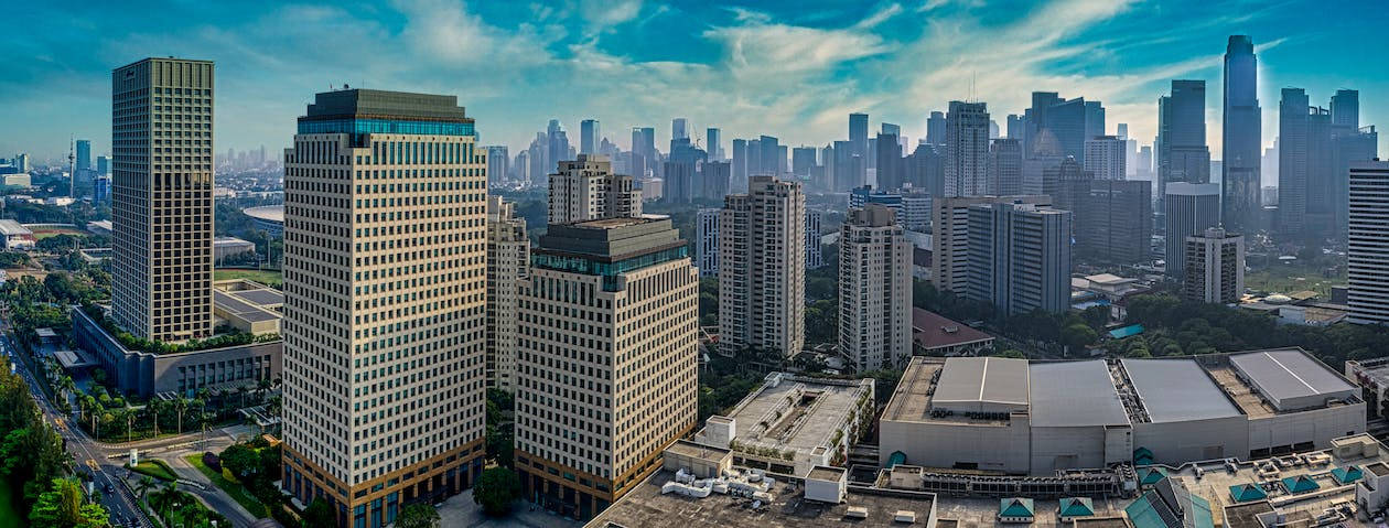 Facebook Cover 桌布 壁紙 — 現代摩天大樓和城市基礎設施的鳥瞰圖，背景是充滿活力的藍天和縷縷白雲。