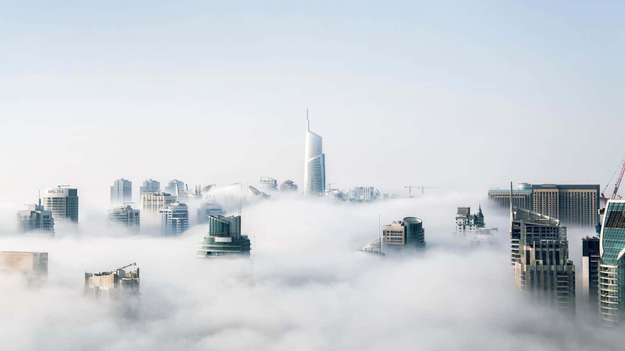 1280x720 桌布 壁紙 — 現代摩天大樓在淡藍色天空下穿透厚厚的霧毯。