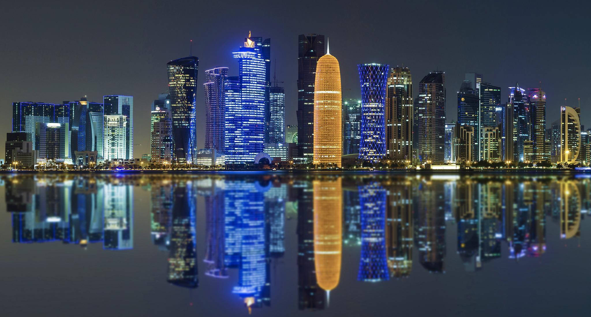 城市 桌布 壁紙 — 現代摩天大樓的迷人夜景，充滿活力的藍色和金色燈光完美地倒映在平靜的水面上。