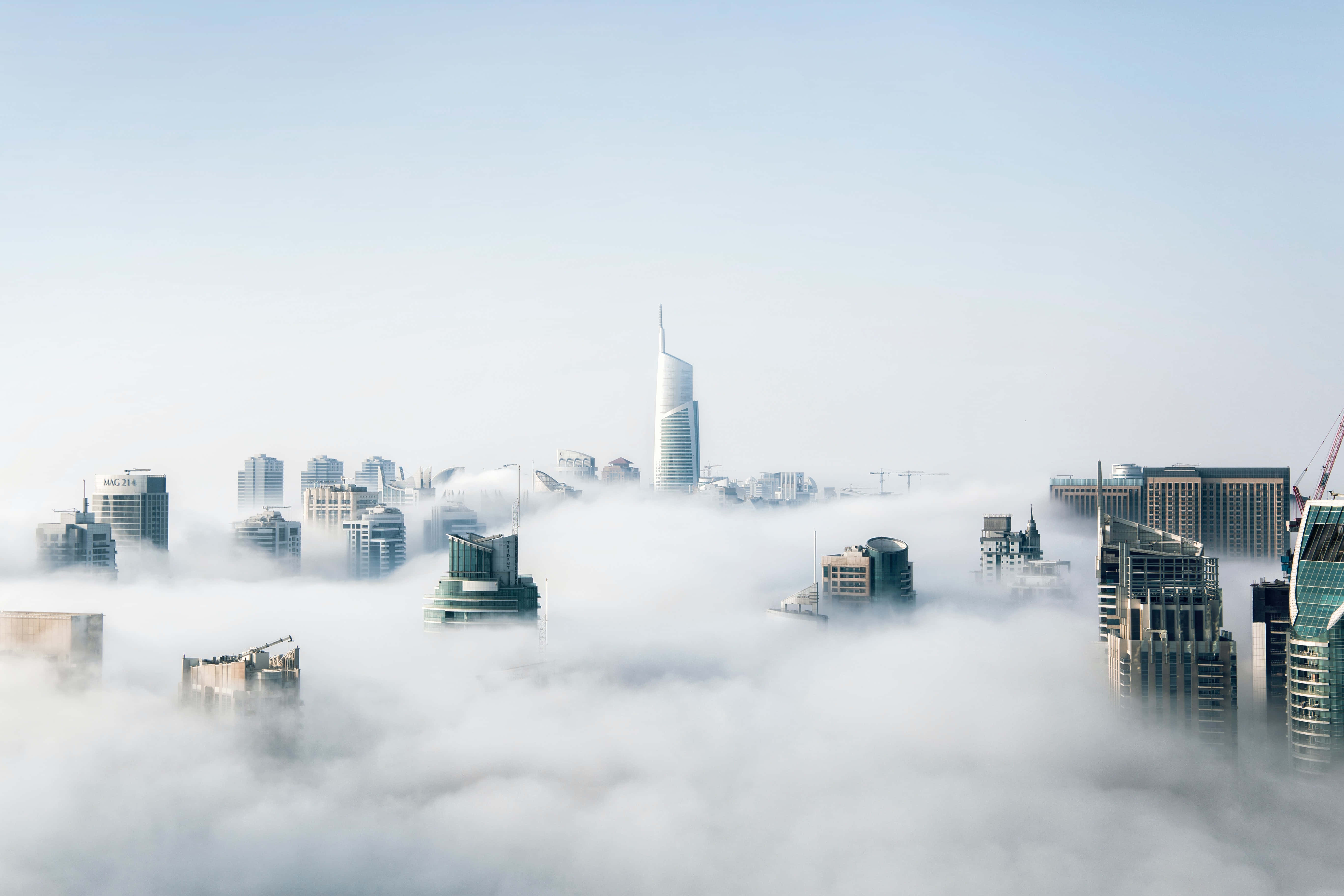 Foggy 桌布 壁紙 — 現代摩天大樓穿透濃厚的晨霧，營造出寧靜而神秘的城市天際線。