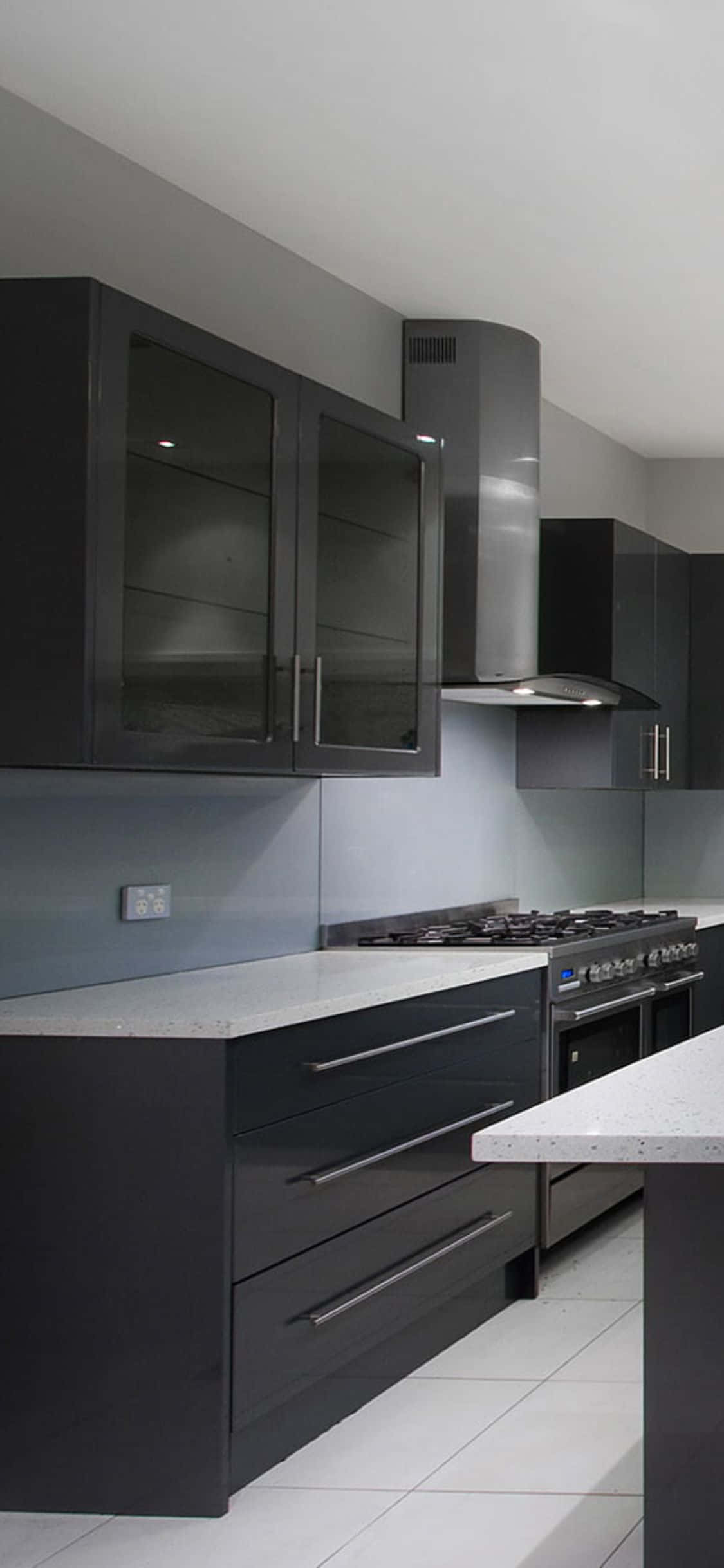 kitchen 桌布 壁紙 — 現代時尚黑色廚房櫥櫃，配有玻璃門和不鏽鋼電器，在明亮的頂燈下。