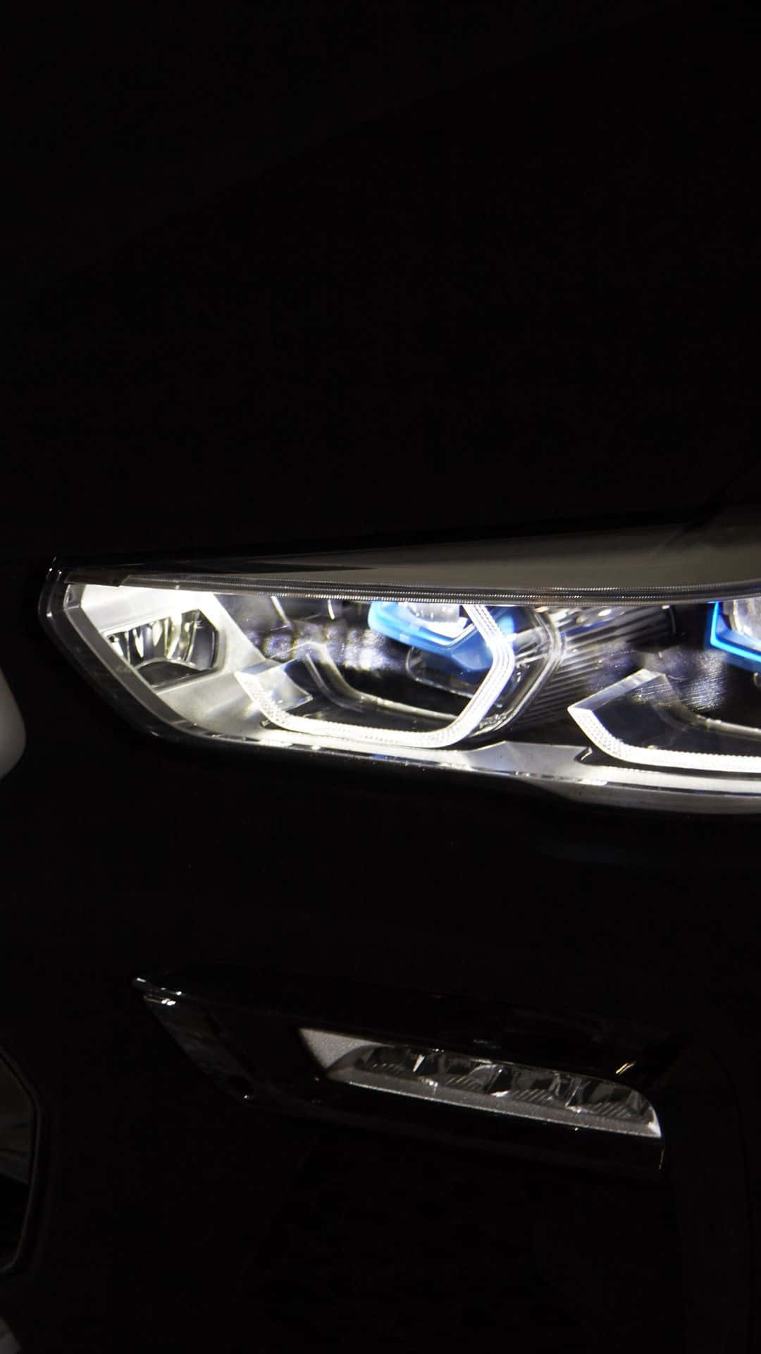 Vantablack 桌布 壁紙 — 現代汽車亮起的車頭燈特寫，在漆黑背景下發出明亮的白色和藍色光芒。