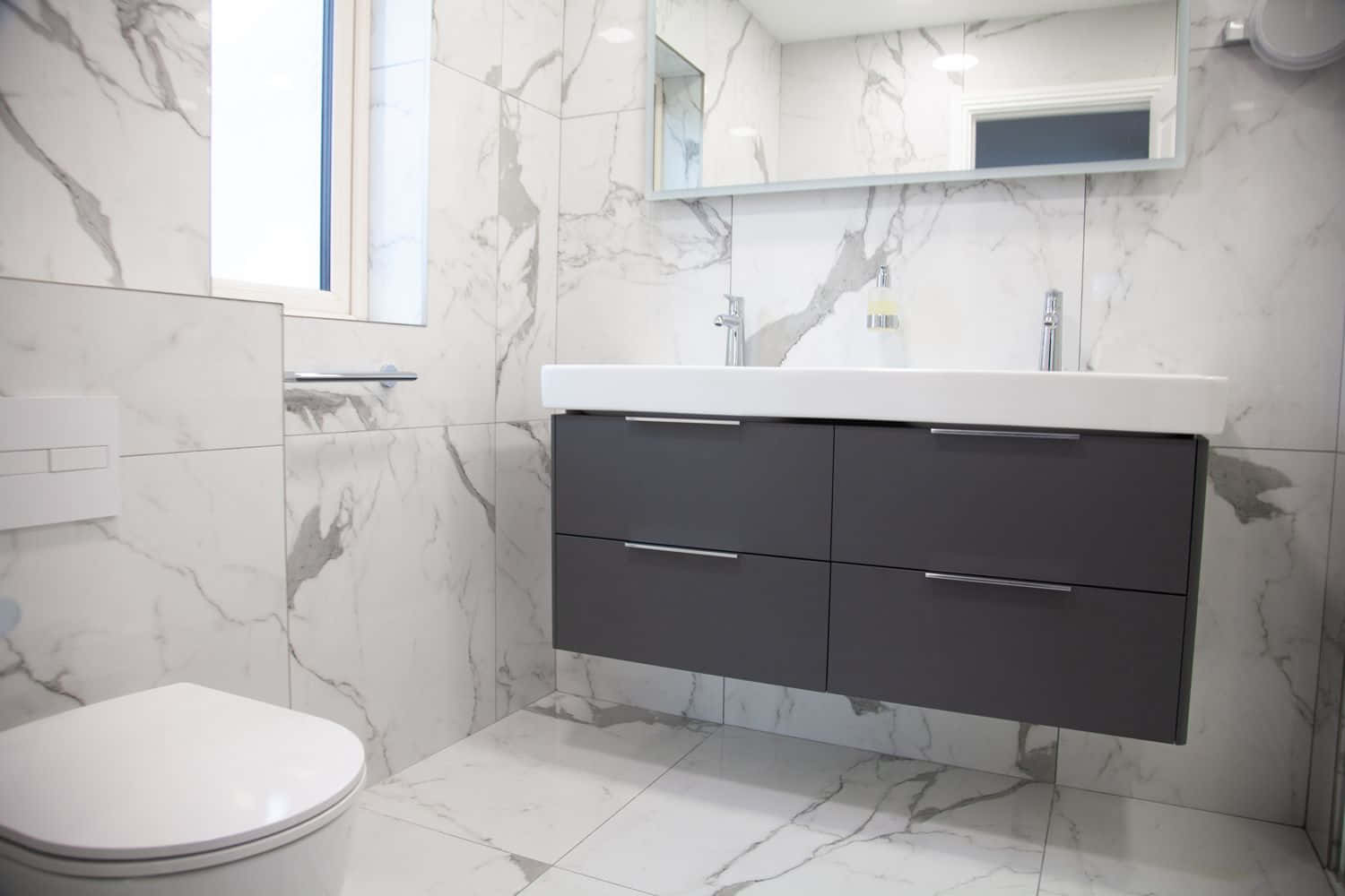 Black And White Bathroom 桌布 壁紙 — 現代浴室，白色大理石牆壁和地板，懸浮深灰色洗手台，窗戶帶來明亮自然光。