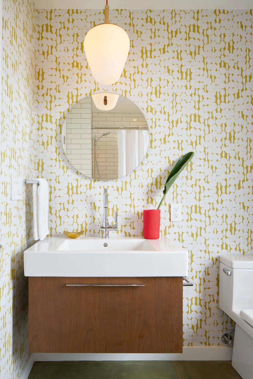 Bathroom Decor 桌布 壁紙 — 現代浴室，配有黃色圖案壁紙、白色洗手台、木製梳妝台和吊燈下的圓形鏡子。