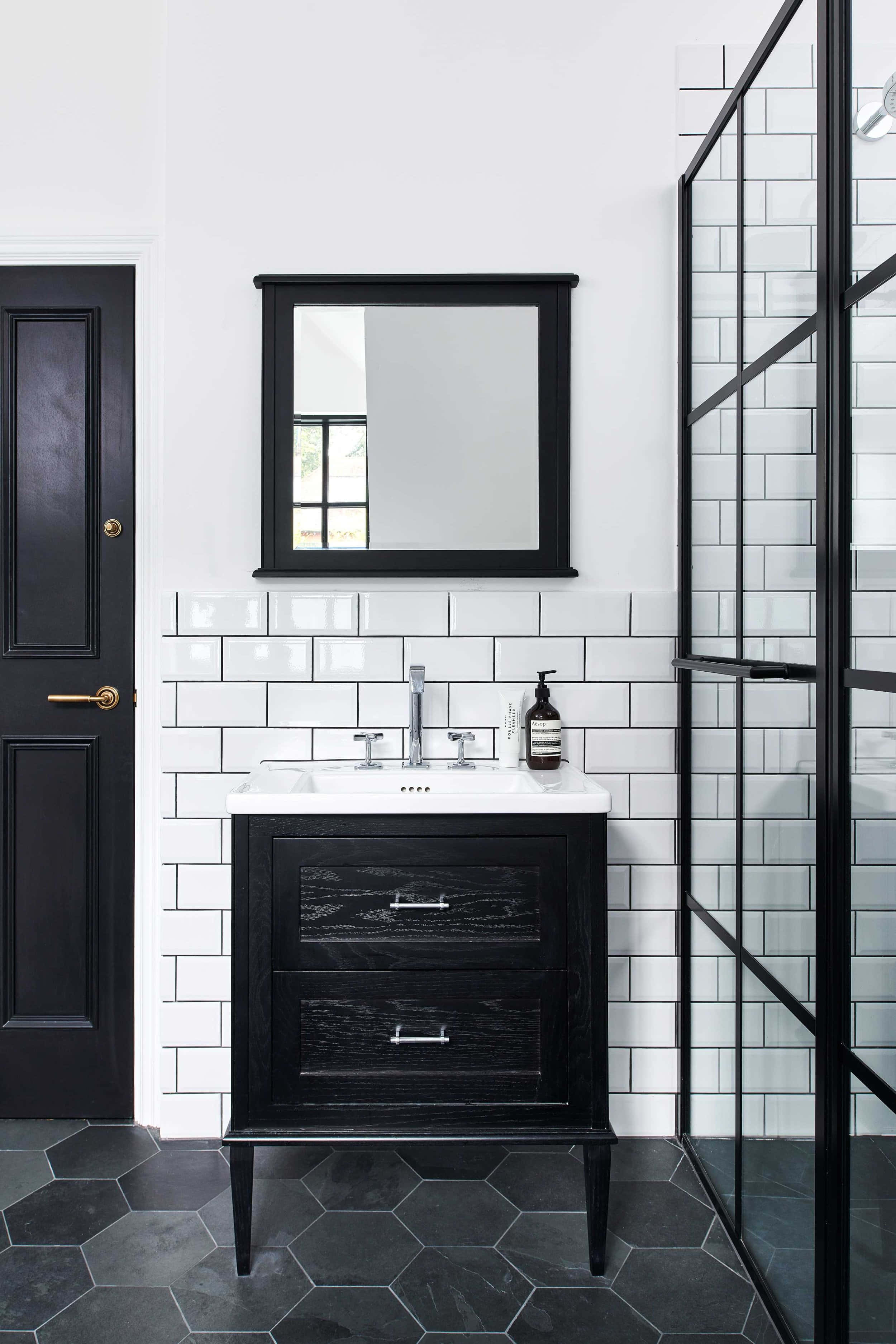 Black And White Bathroom 桌布 壁紙 — 現代浴室，配有黑色洗手台、白色地鐵磚和六角形地板磚，在明亮的日光下。