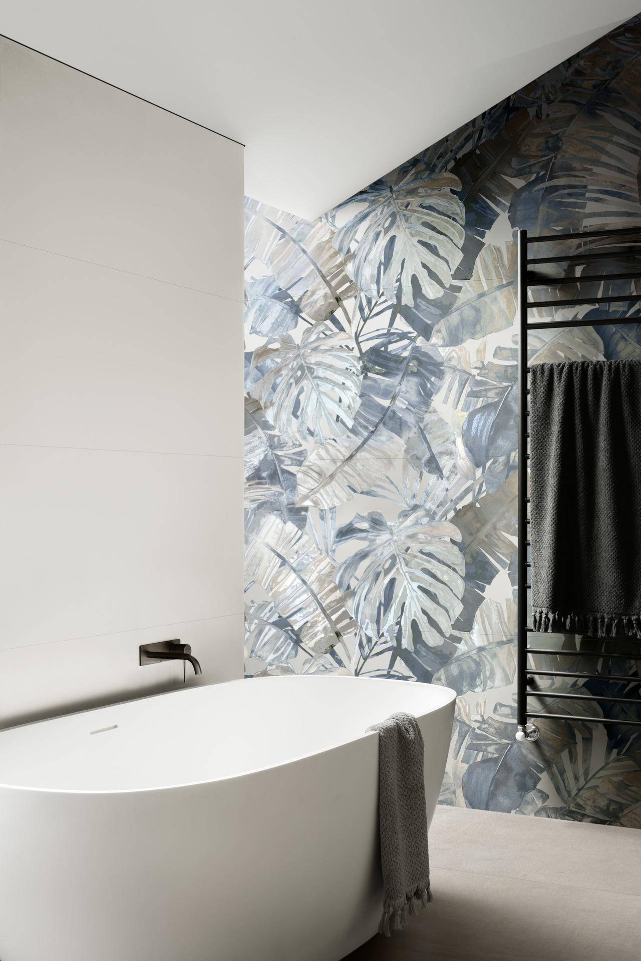 bathroom 桌布 壁紙 — 現代浴室設有一個獨立式白色浴缸，旁邊的牆上覆蓋著大型龜背竹葉壁紙，採用柔和的藍色和灰色。