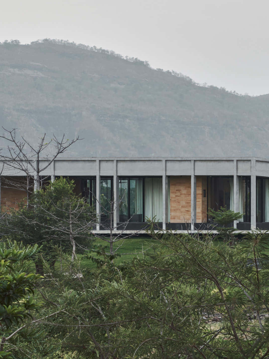 Minimalist Architecture 桌布 壁紙 — 現代混凝土房屋，玻璃牆，坐落在茂密綠植中，背景是霧氣繚繞的山巒。