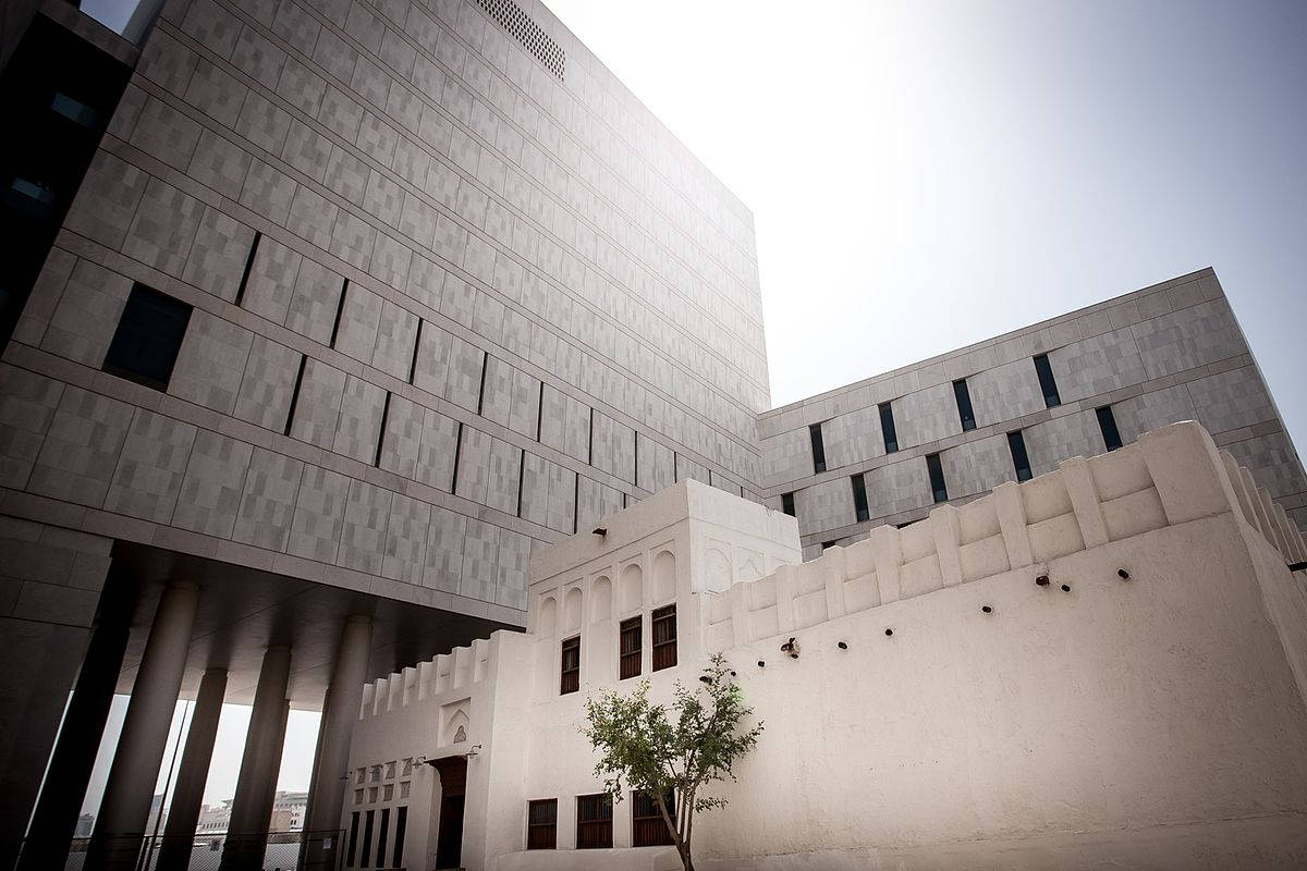 Qatar 桌布 壁紙 — 現代混凝土摩天大樓聳立於傳統白色牆壁建築之上，前景有一棵小樹。