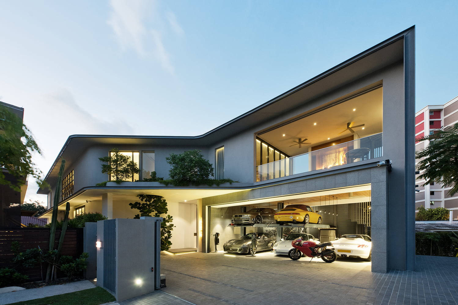 Luxury House 桌布 壁紙 — 現代灰色房屋，開放式車庫展示豪華汽車和一輛紅色摩托車，背景為暮色天空。