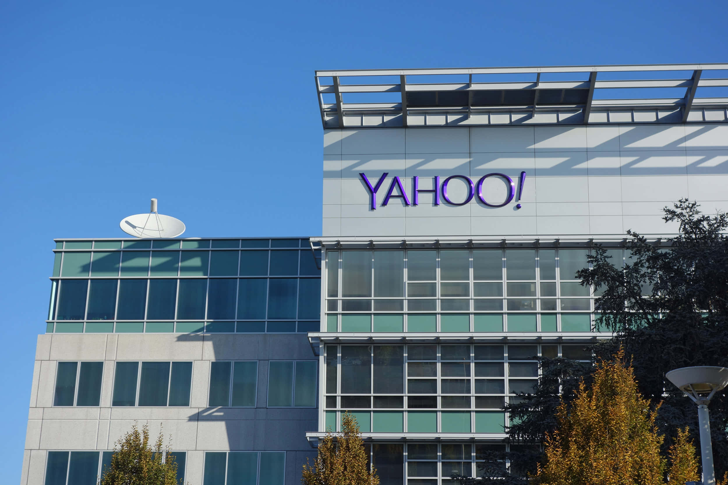 Yahoo 桌布 壁紙 — 現代玻璃和鋼結構的Yahoo辦公大樓，在晴朗藍天下，前景有秋樹。