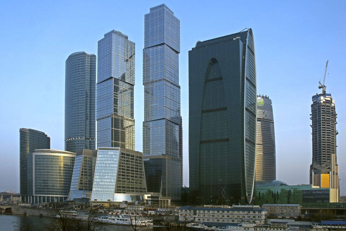 莫斯科 桌布 壁紙 — 現代玻璃摩天大樓在繁華的城市天際線中反射藍天和河上的船隻。