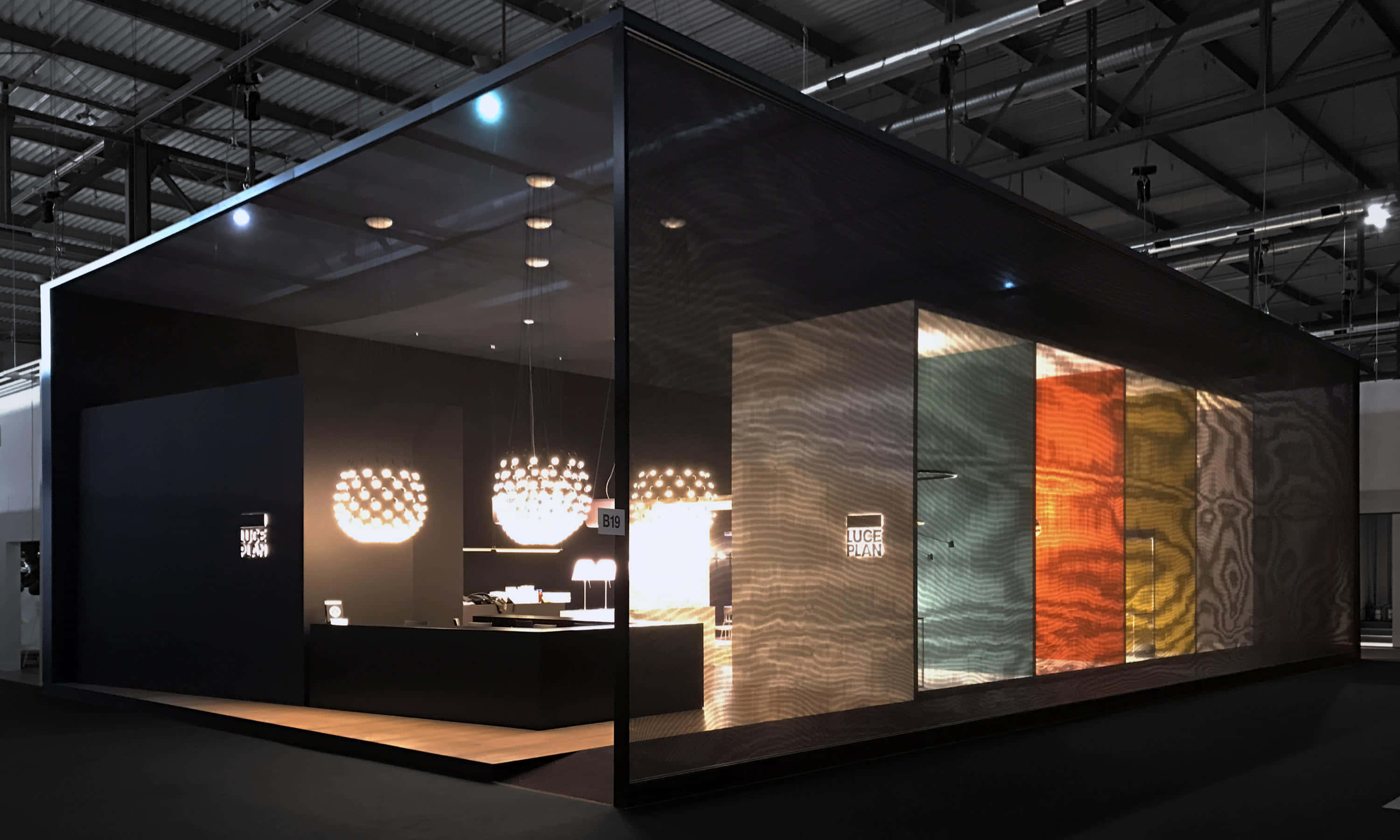 Exhibition 桌布 壁紙 — 現代玻璃牆展廳在工業天花板燈光下展示發光吊燈和紋理面板。
