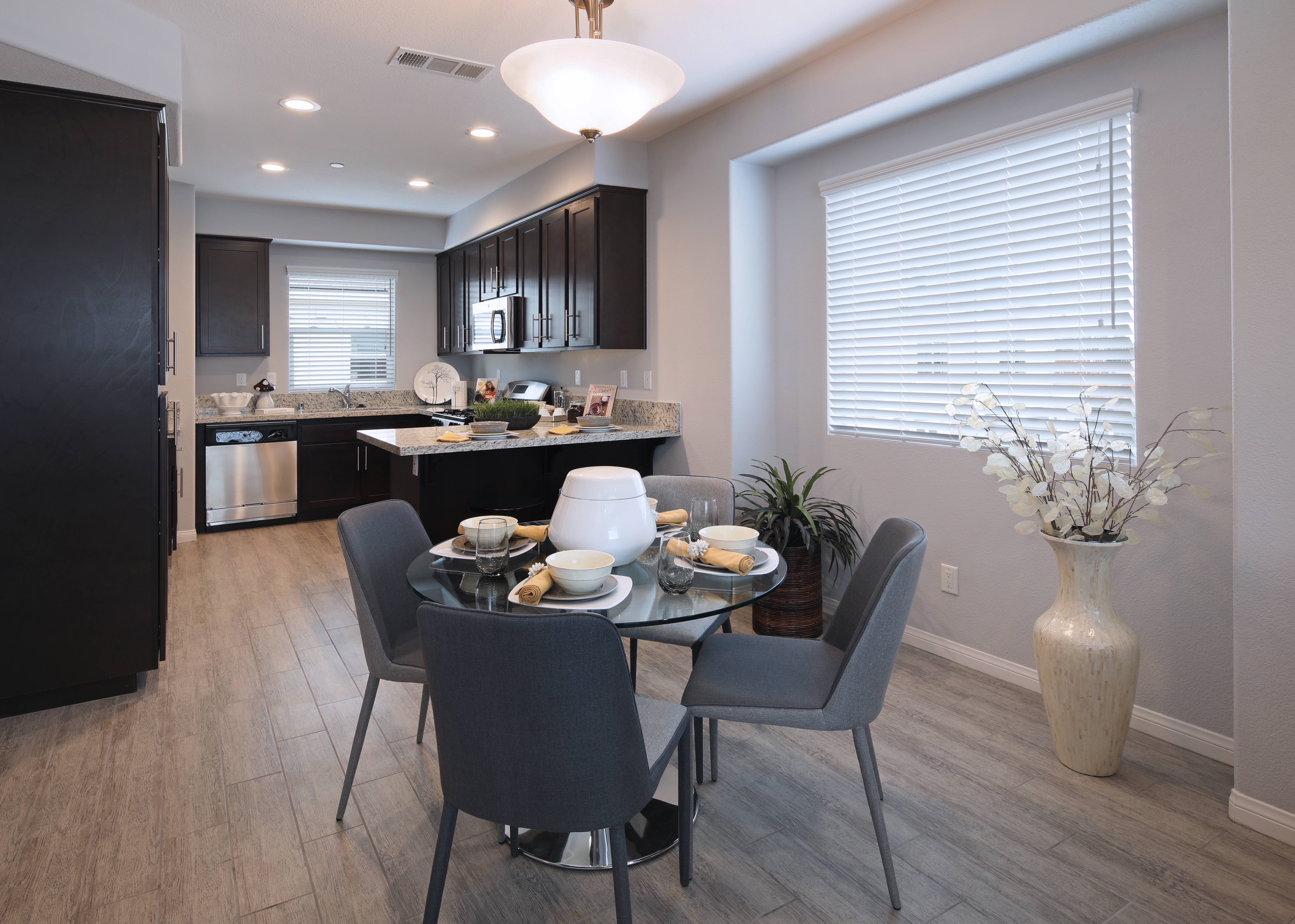 Kitchen Design 桌布 壁紙 — 現代用餐區，配有玻璃餐桌、灰色椅子及深色木質廚房，在明亮的日光下。