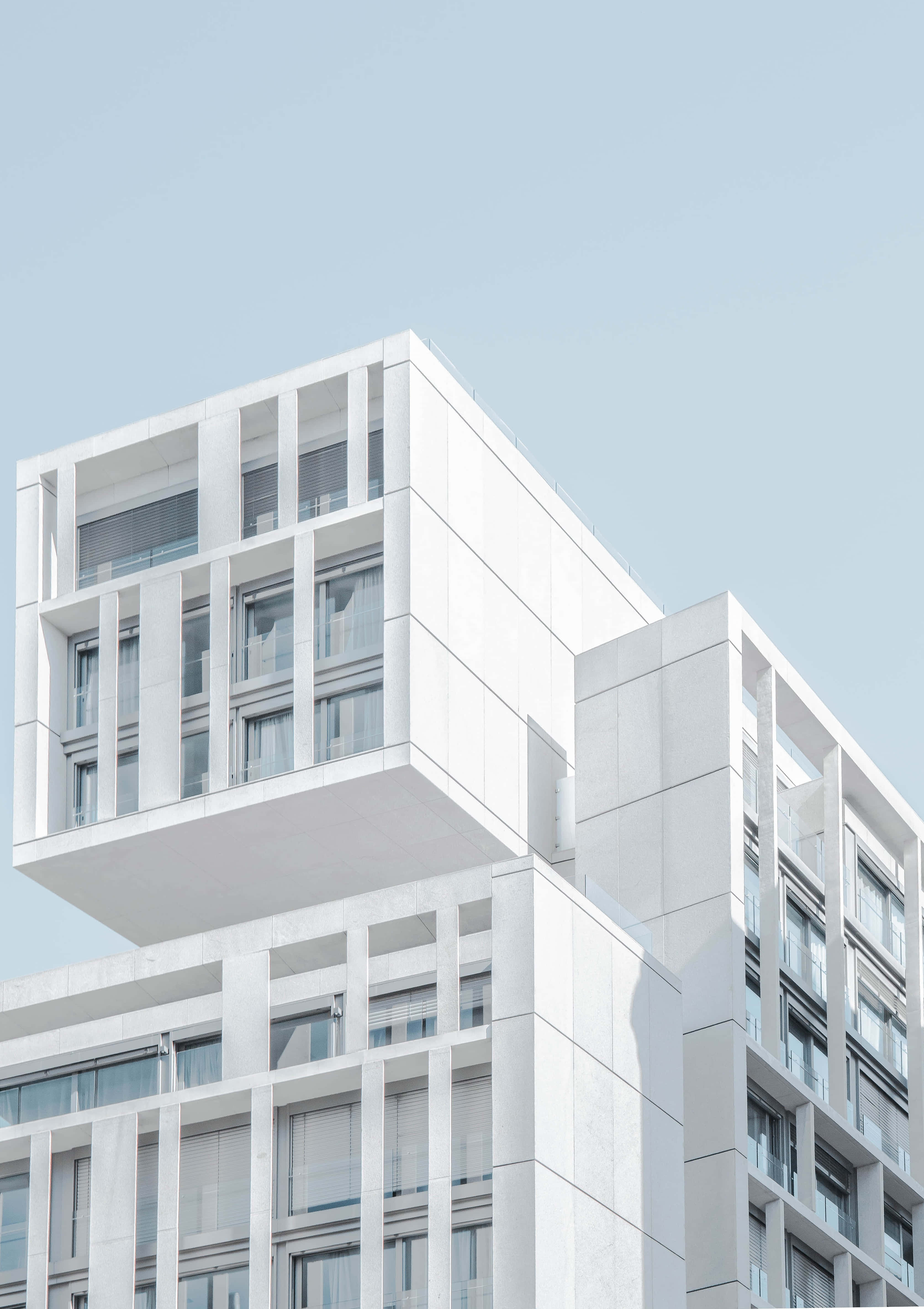 Building 桌布 壁紙 — 現代白色建築結構，帶有幾何陽台，襯托著清澈的淡藍色天空。