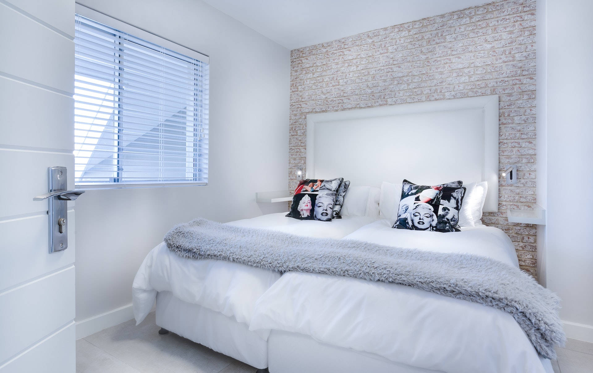 bed 桌布 壁紙 — 現代白色臥室，床鋪配有瑪麗蓮夢露枕頭，背景是紋理磚牆。