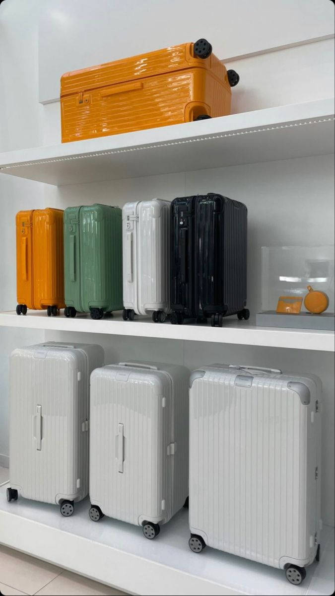 Shelves 桌布 壁紙 — 現代硬殼行李箱以鮮豔的橙色、綠色、白色和黑色整齊地排列在潔白的貨架上，呈現極簡的零售展示。
