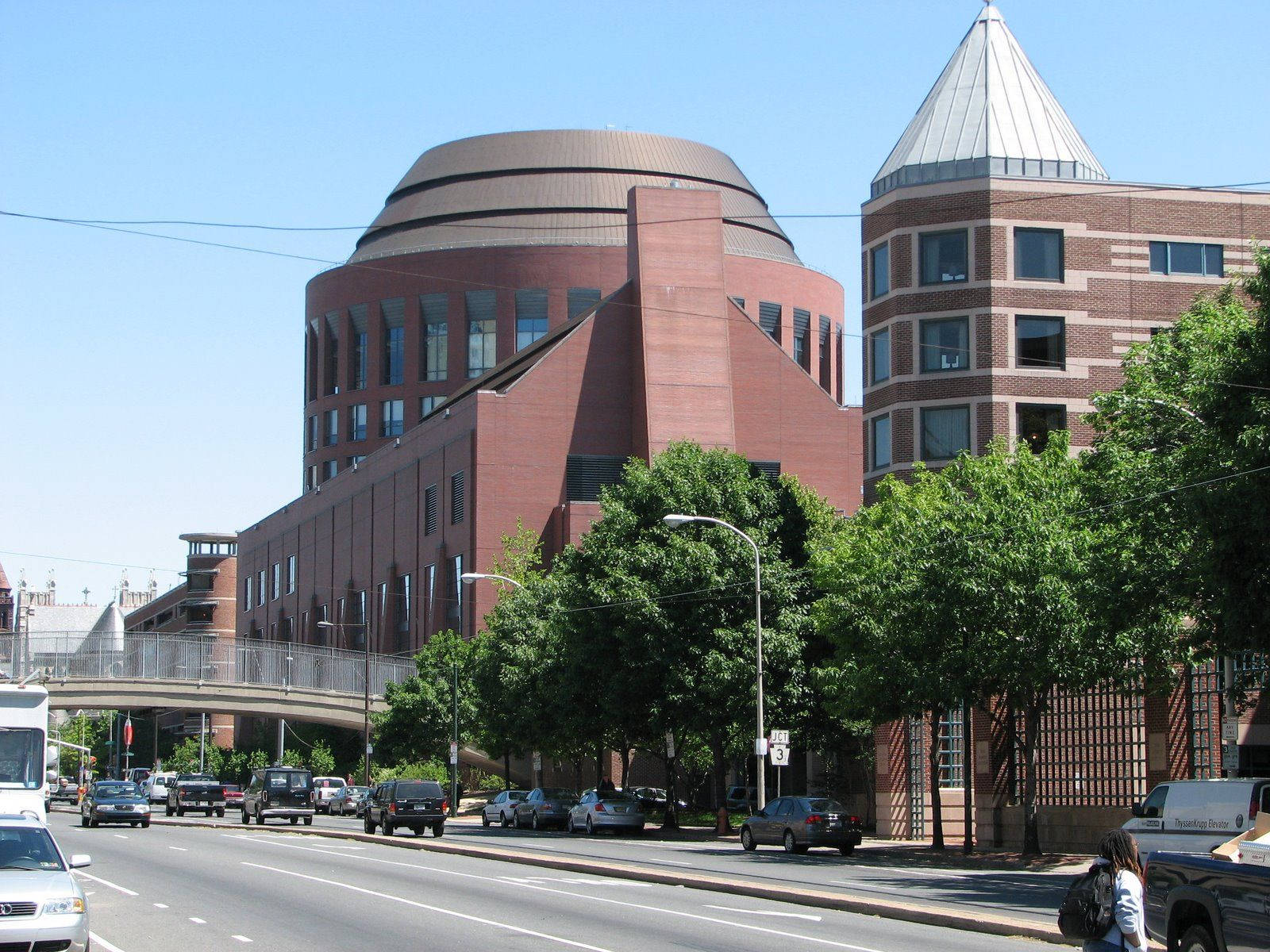 University Of Pennsylvania 桌布 壁紙 — 現代磚砌建築，擁有圓頂和圓錐形屋頂，矗立於林蔭大道旁，汽車和行人穿梭其間，頭頂是清澈的藍天。