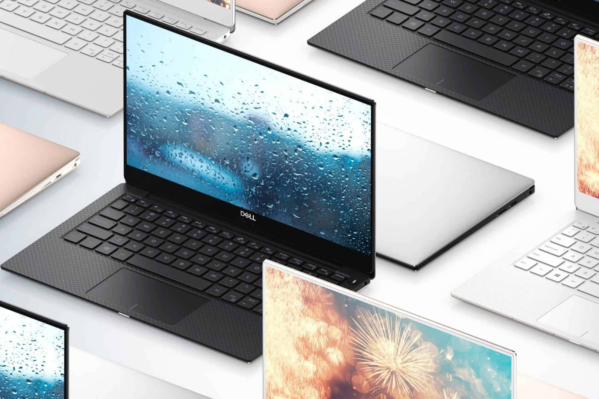 Dell 桌布 壁紙 — 現代筆記型電腦，配備多種螢幕，顯示雨滴和煙火，整齊排列在潔白的表面上。