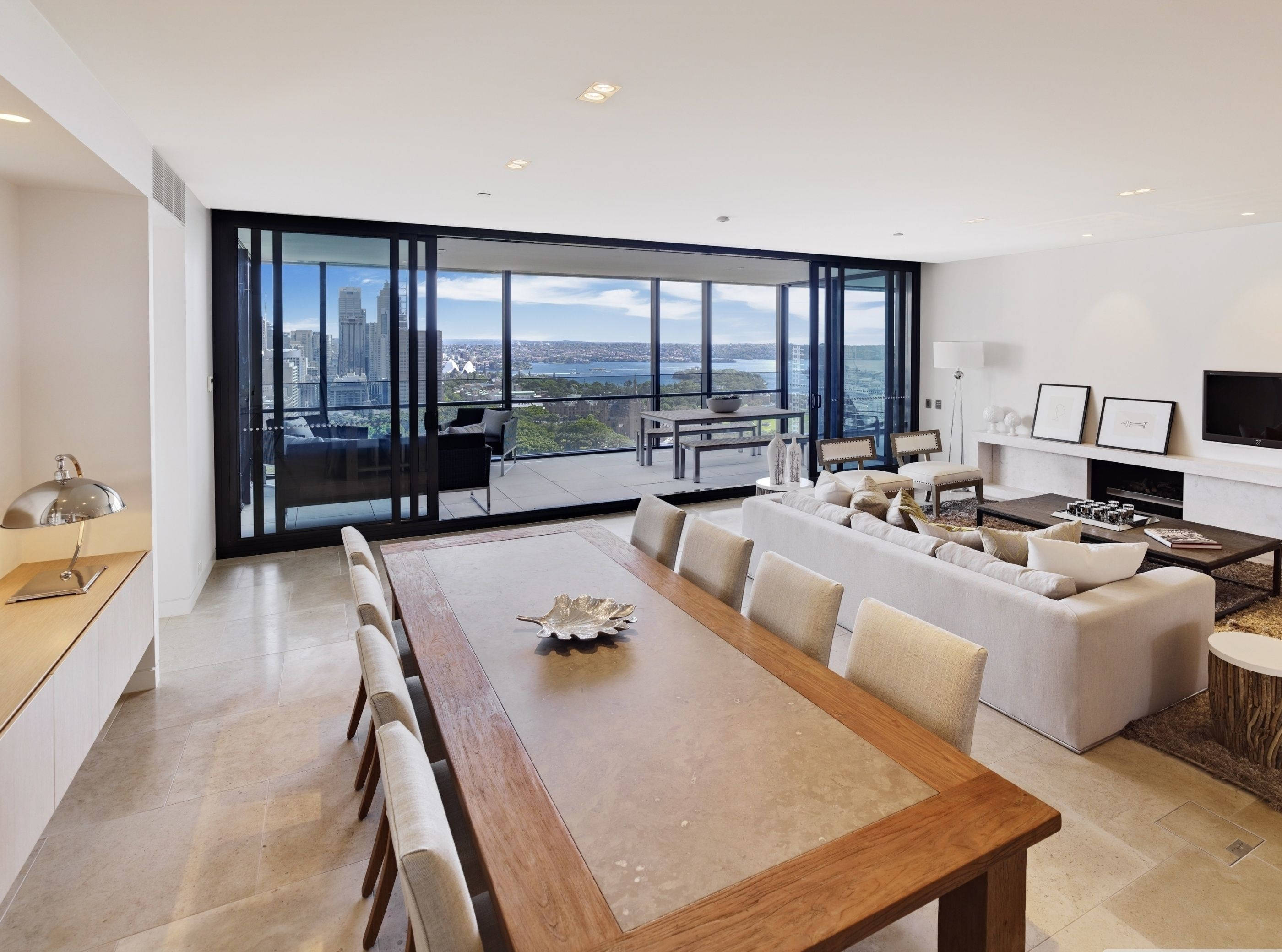Apartment 桌布 壁紙 — 現代簡約客廳，設有大型玻璃門，可欣賞晴朗藍天下的城市景觀和港口。