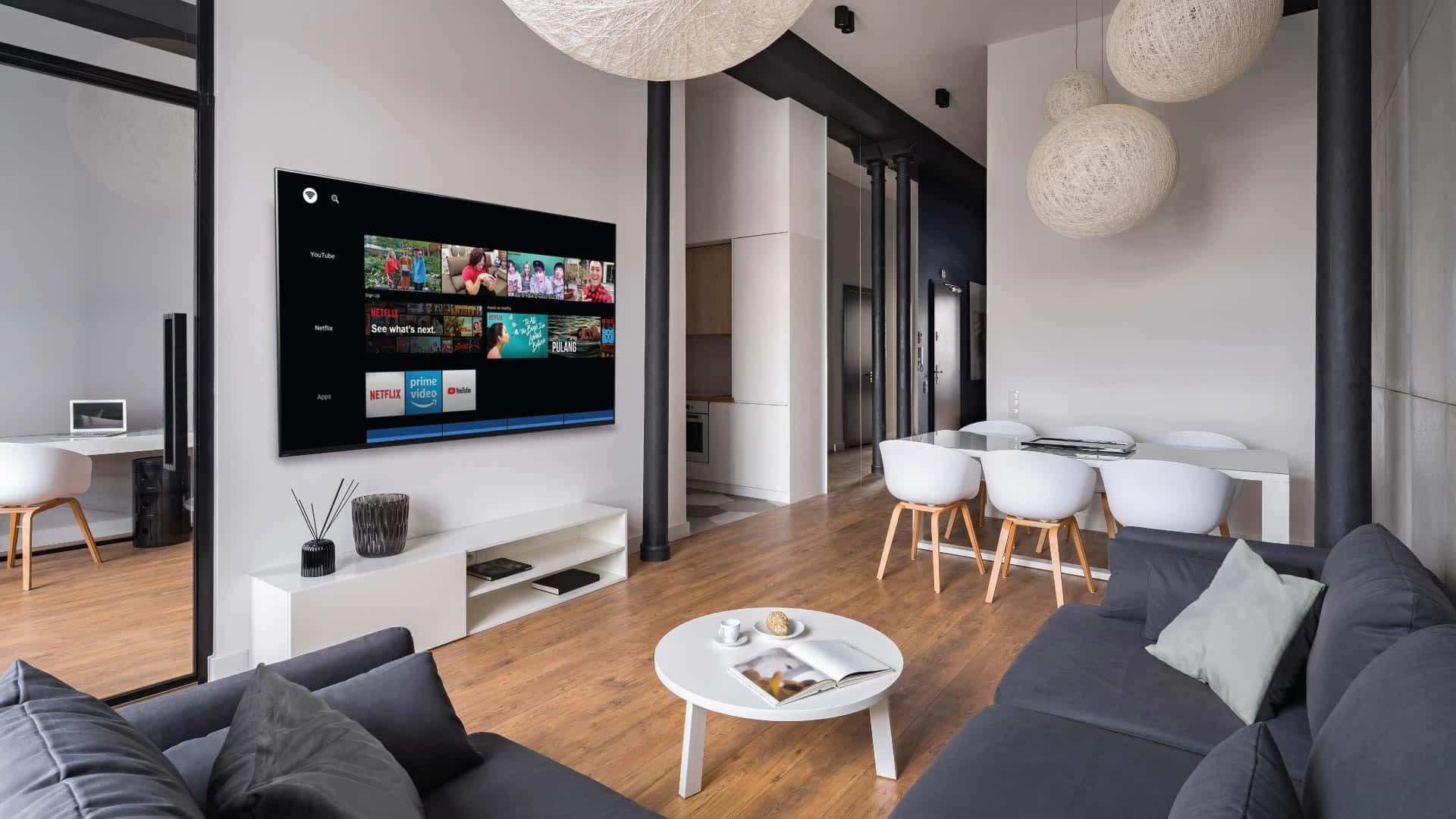 Home Entertainment 桌布 壁紙 — 現代簡約客廳，配有灰色沙發、白色餐椅和大螢幕電視，顯示串流應用程式。