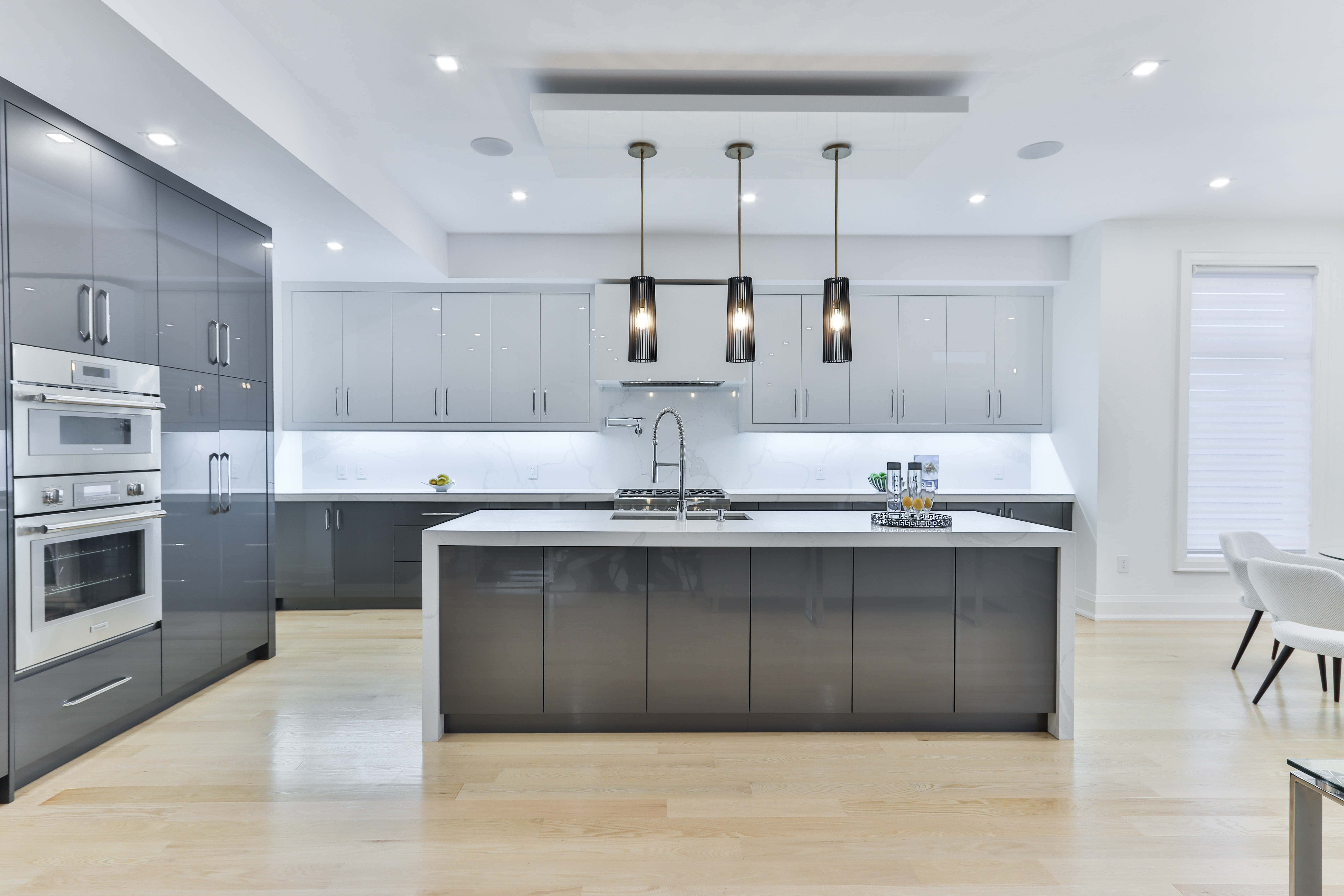kitchen 桌布 壁紙 — 現代簡約廚房，配備時尚灰色櫥櫃、白色檯面和溫暖木地板，吊燈下。