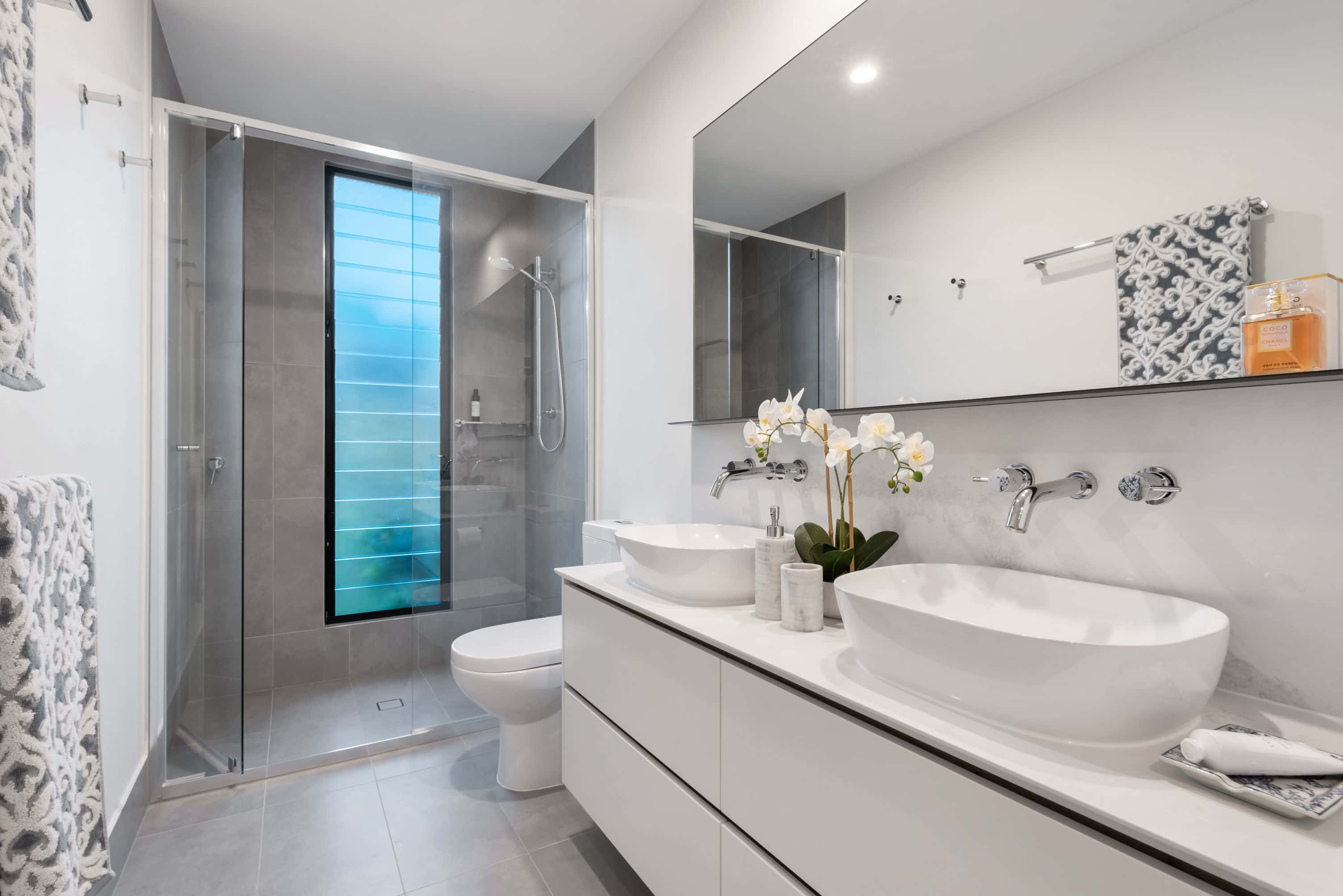 bathroom 桌布 壁紙 — 現代簡約浴室，配有白色檯上盆、玻璃淋浴間和讓自然光透入的藍色調窗戶。