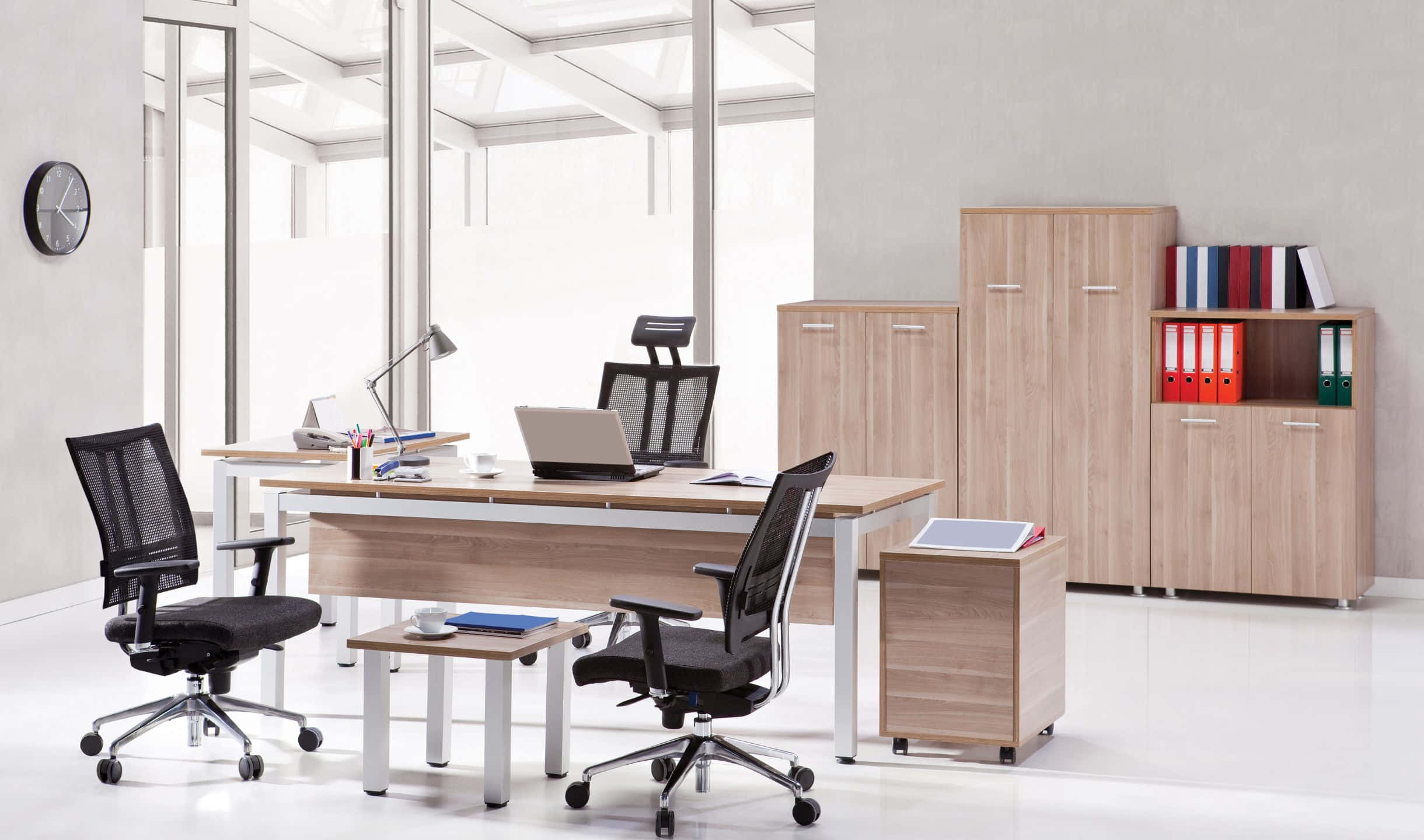 Office Space 桌布 壁紙 — 現代簡約辦公室，配有淺色木桌、黑色網椅和玻璃窗，讓明亮的自然光透入。